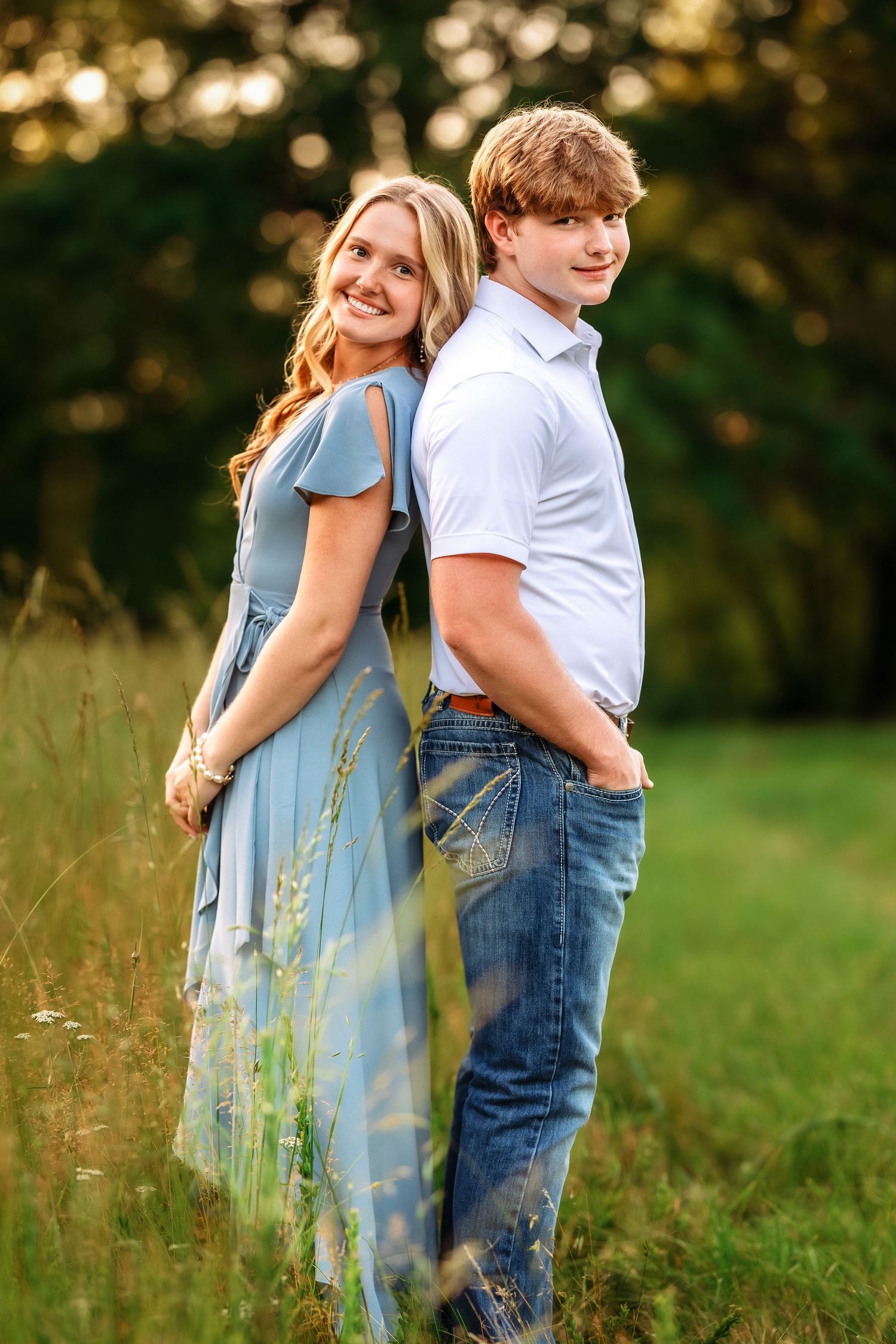 Playful family poses captured in a green meadow with evening light.