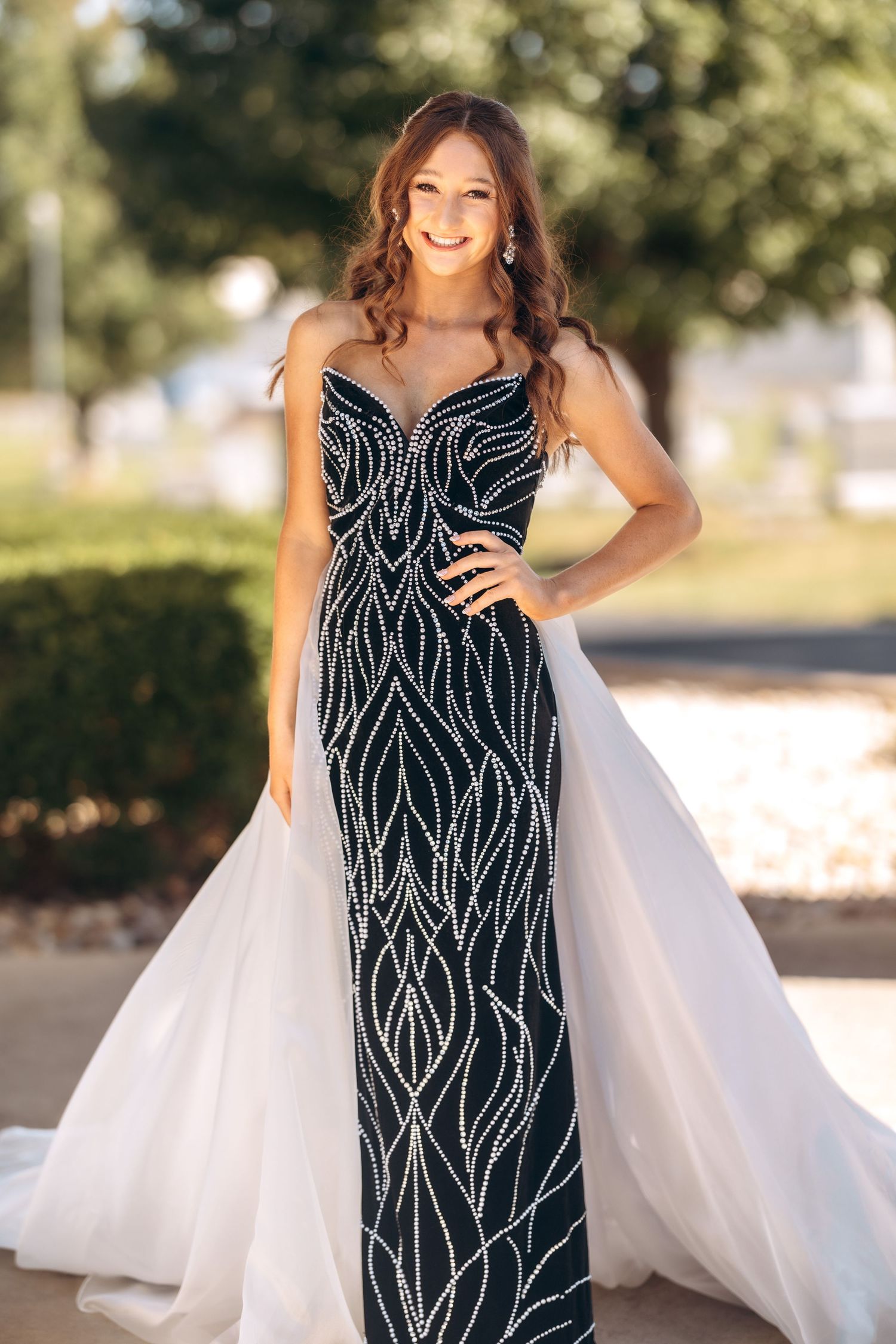 An elegant black beaded gown with white overlay captured in an outdoor setting.