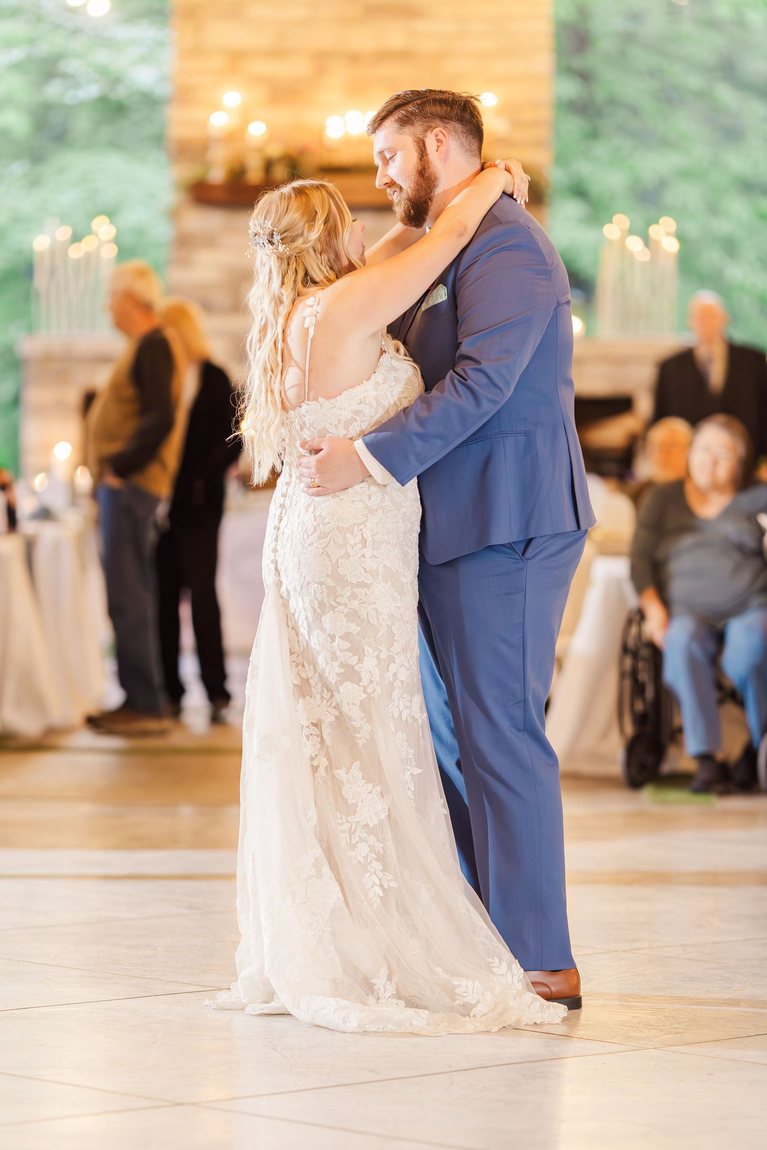 Newlyweds share their first dance in an elegant venue with candlelit backdrop.