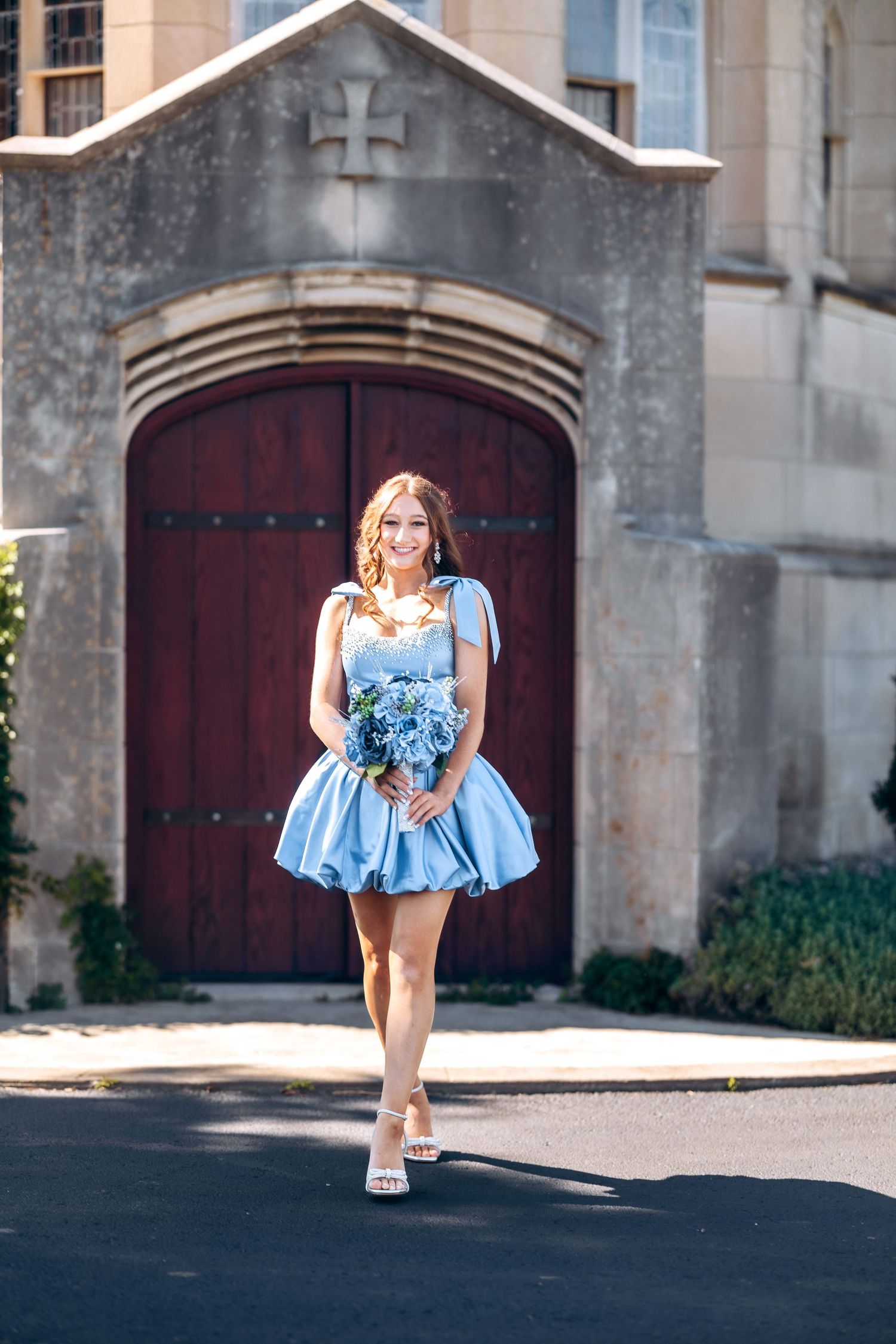 Light blue satin dress with ruffled details captured in front of a historic stone building.