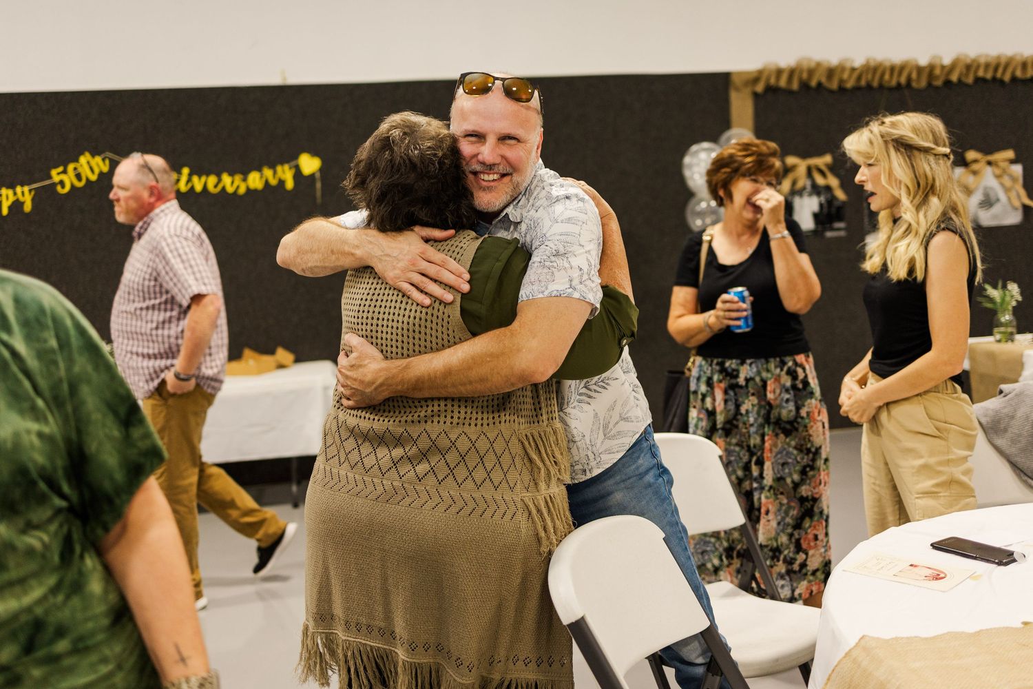People dancing and embracing at a casual indoor celebration event.