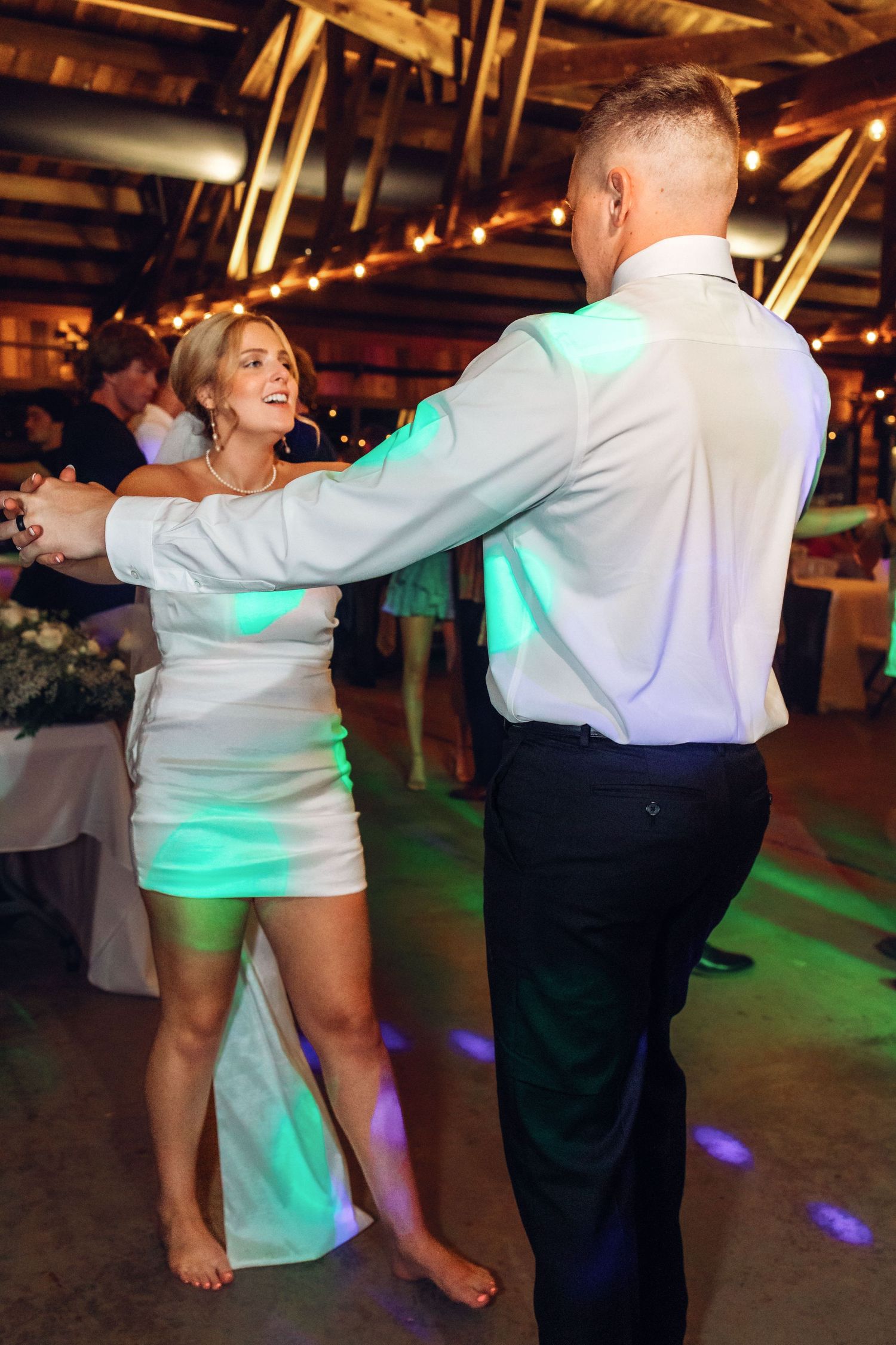 Wedding party dancing barefoot on the reception dance floor with green lighting effects.