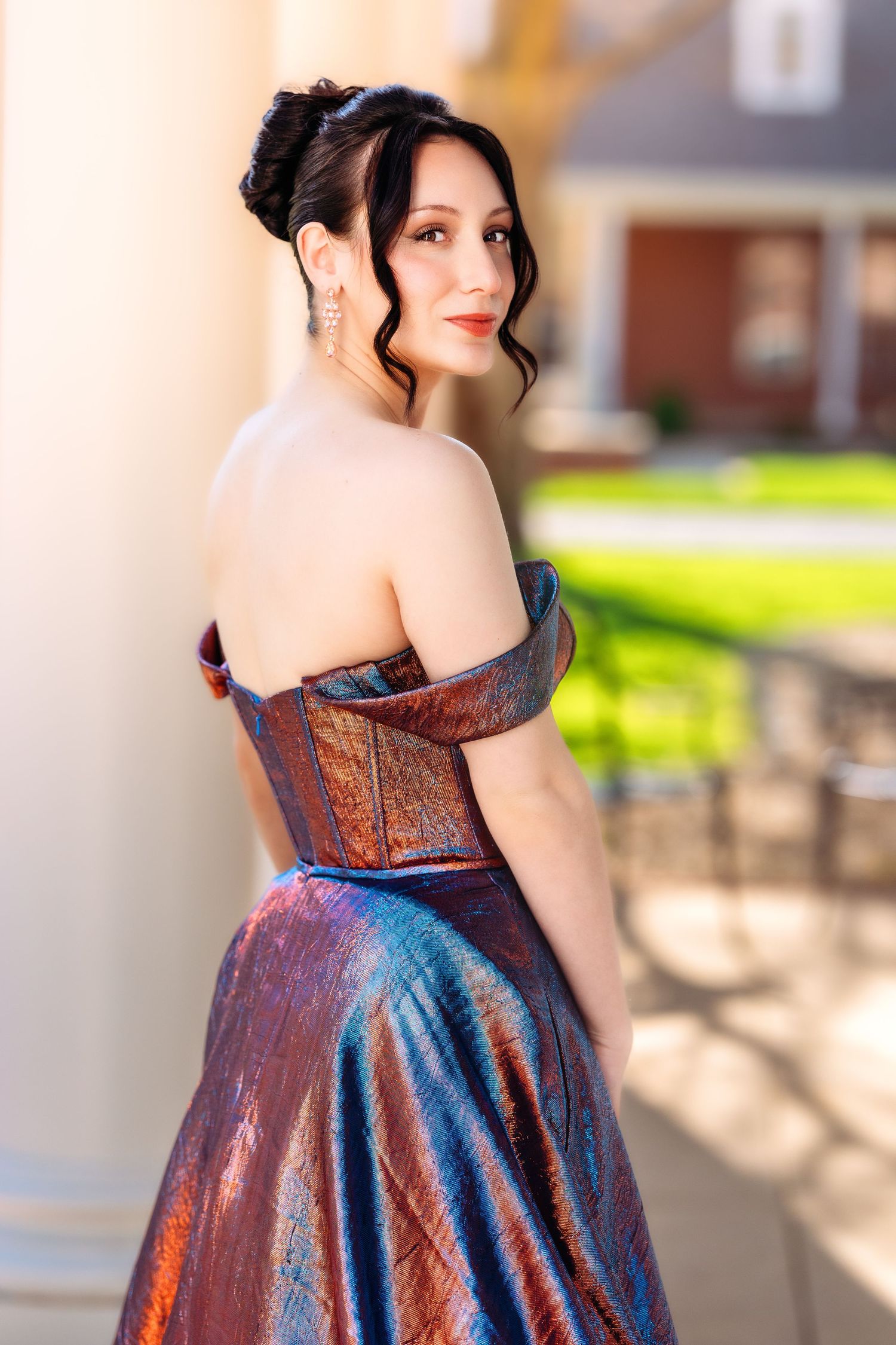A shimmering iridescent blue and copper formal dress with a strapless neckline is shown from multiple angles outdoors.
