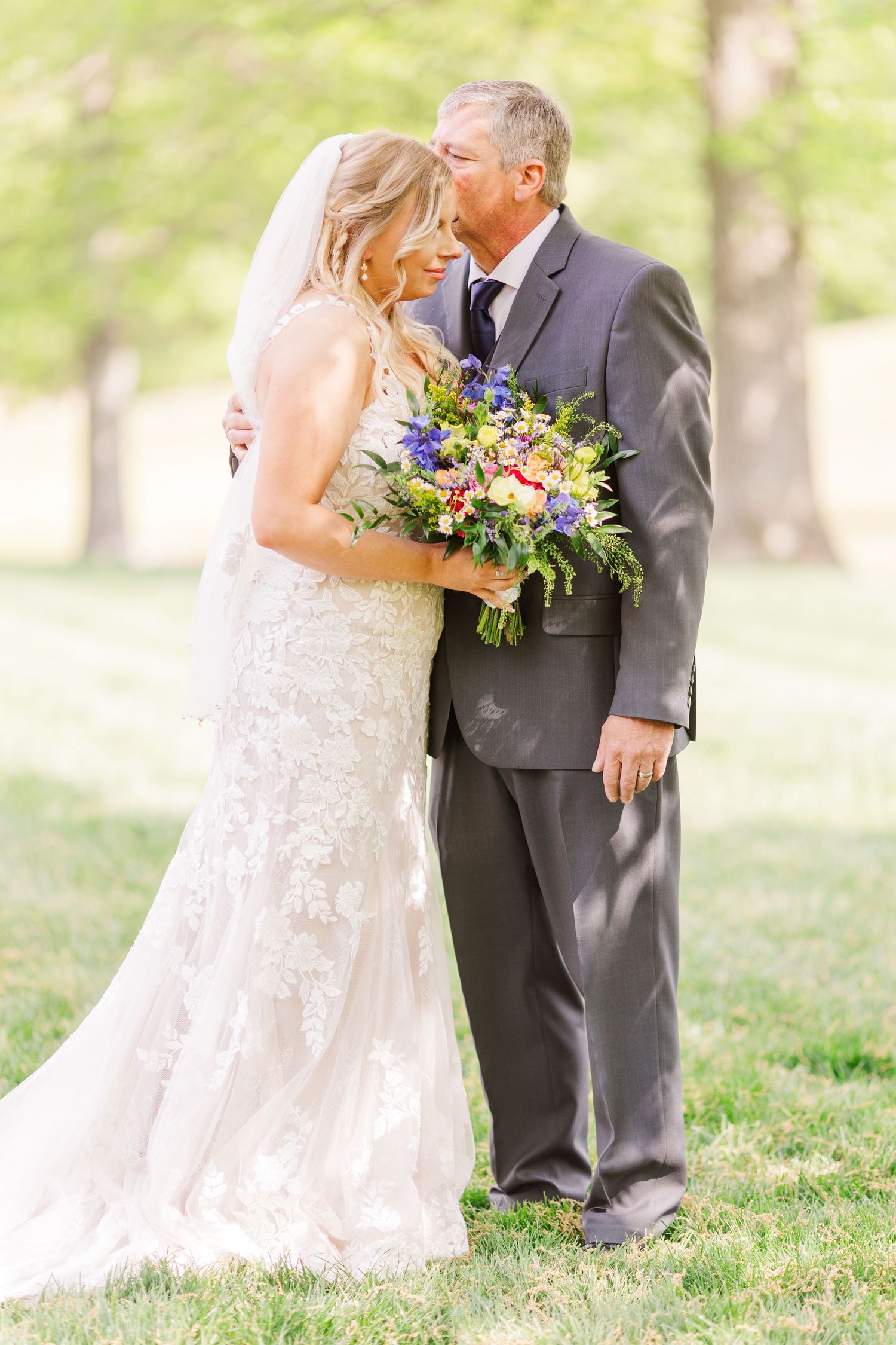 Romantic outdoor wedding portraits in natural sunlit setting with colorful bouquet.