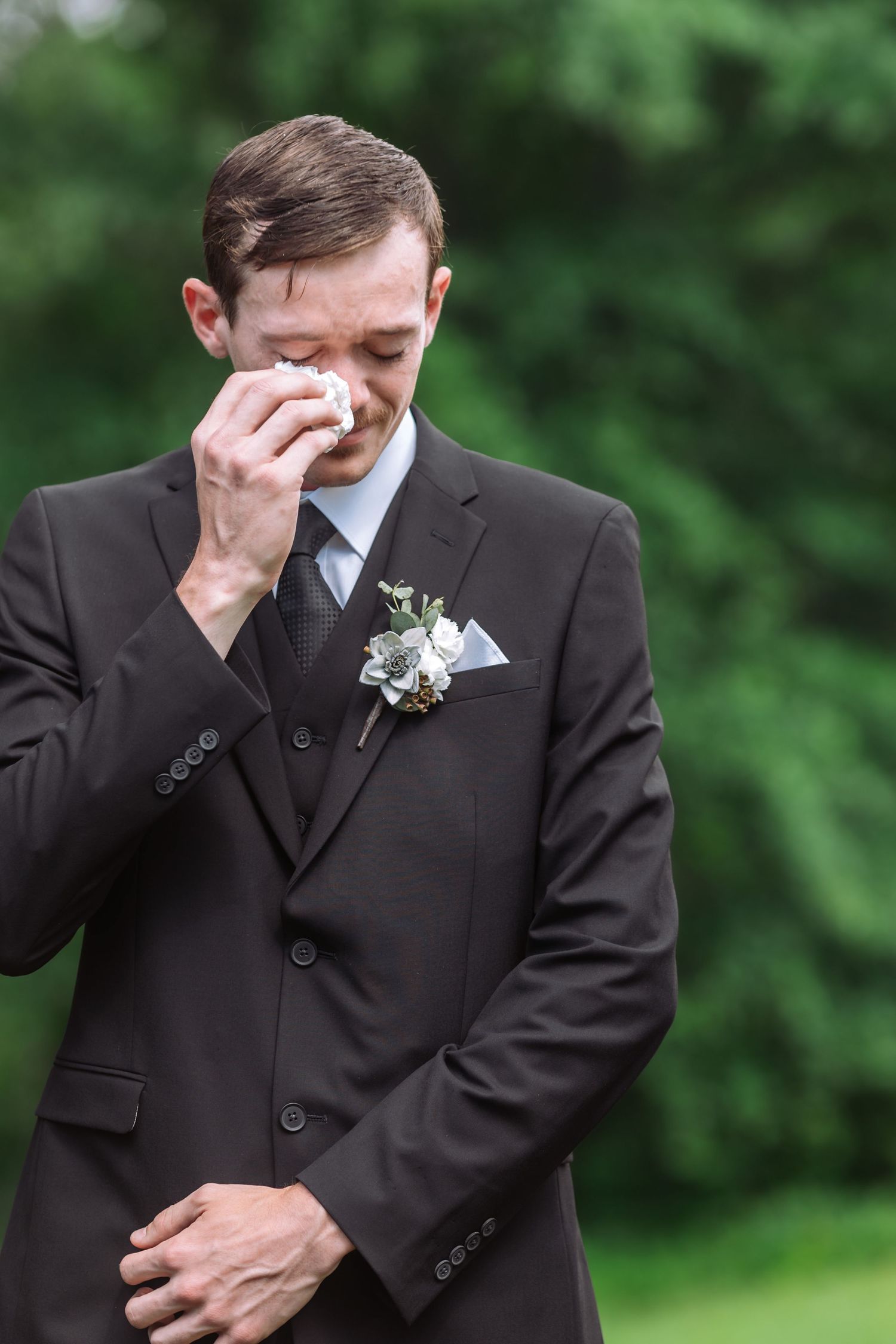 An emotional moment as a groom wipes away tears during the wedding ceremony.