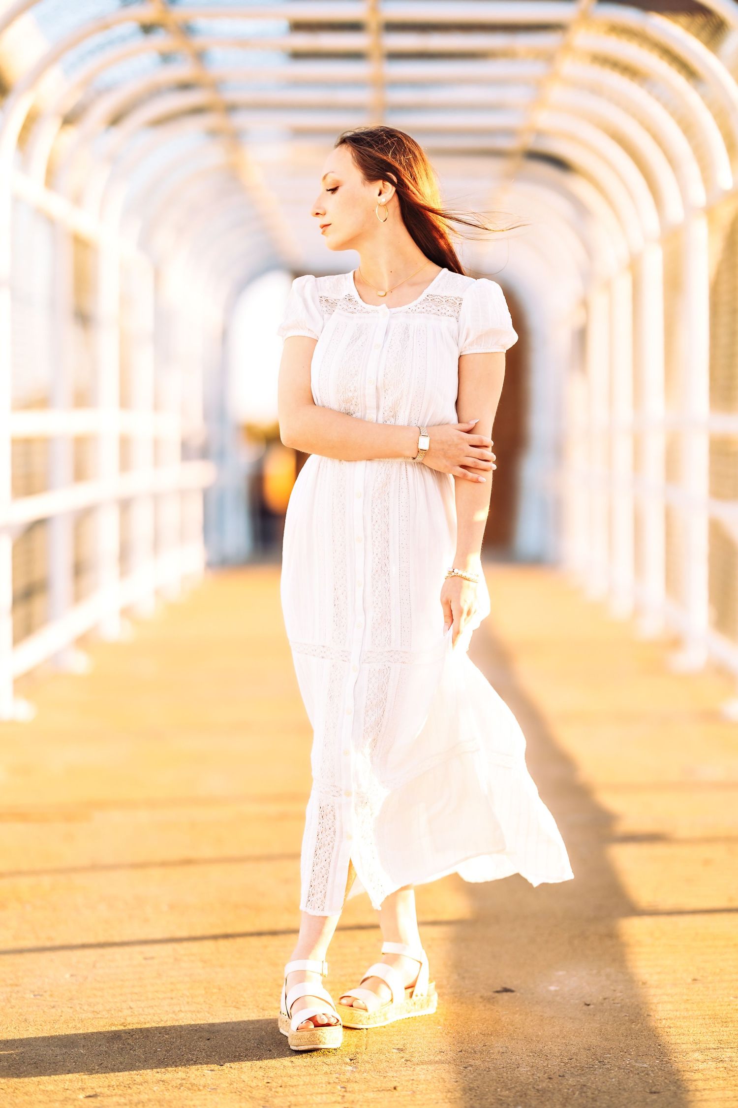A dreamy golden hour photoshoot featuring a white lace dress against a sunlit outdoor backdrop.