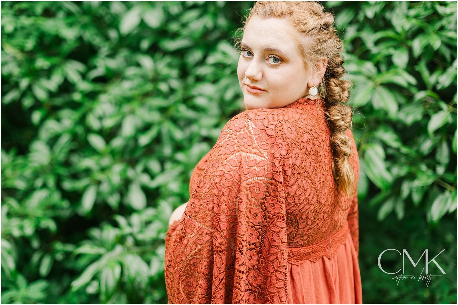Back view of coral lace maternity gown with flowing sleeves against greenery.