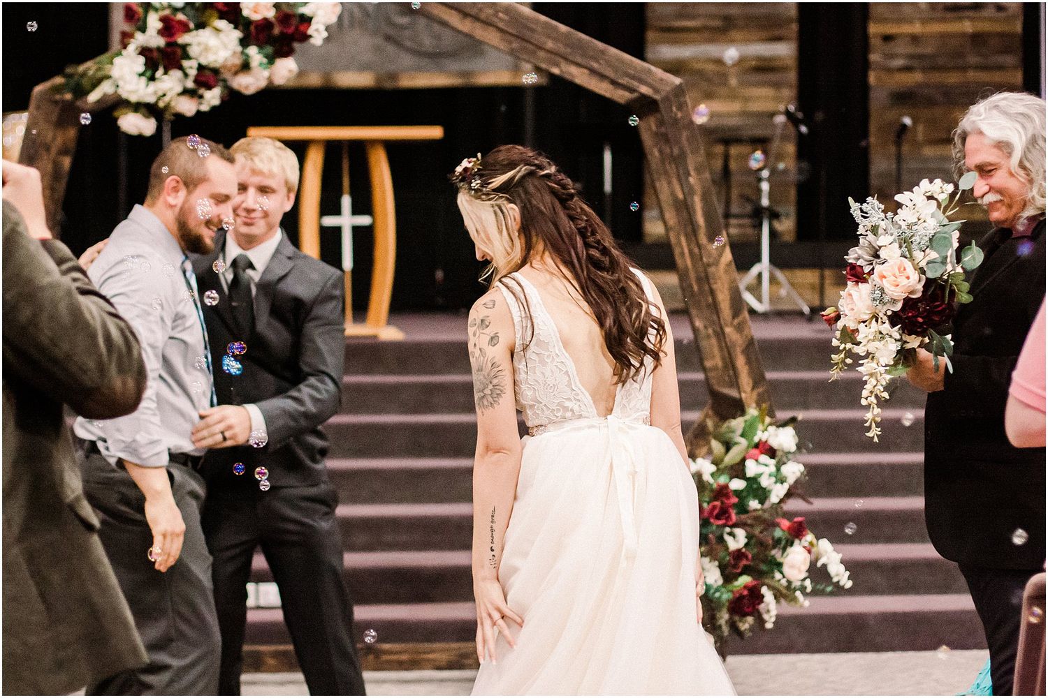 Wedding celebration candid with guests mingling under a floral arch.