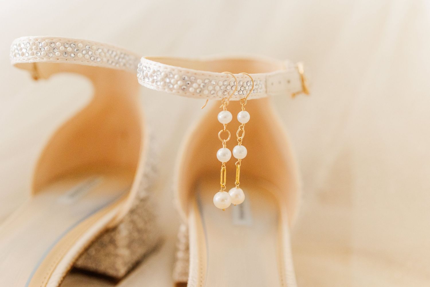 Delicate lace wedding dress details with crystal embellishments on ivory background.