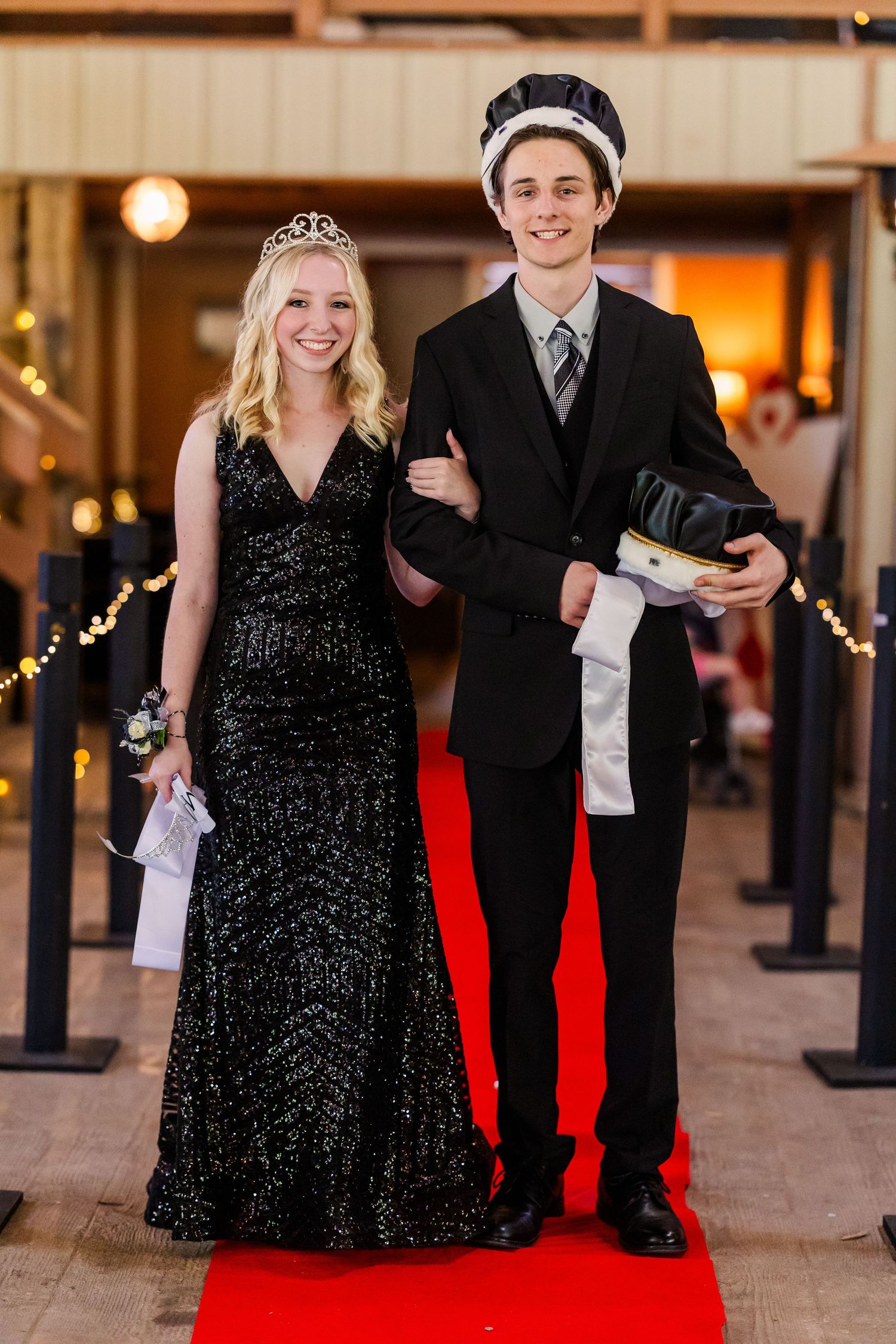 Couples in black formal wear pose on a red carpet at an elegant indoor event.