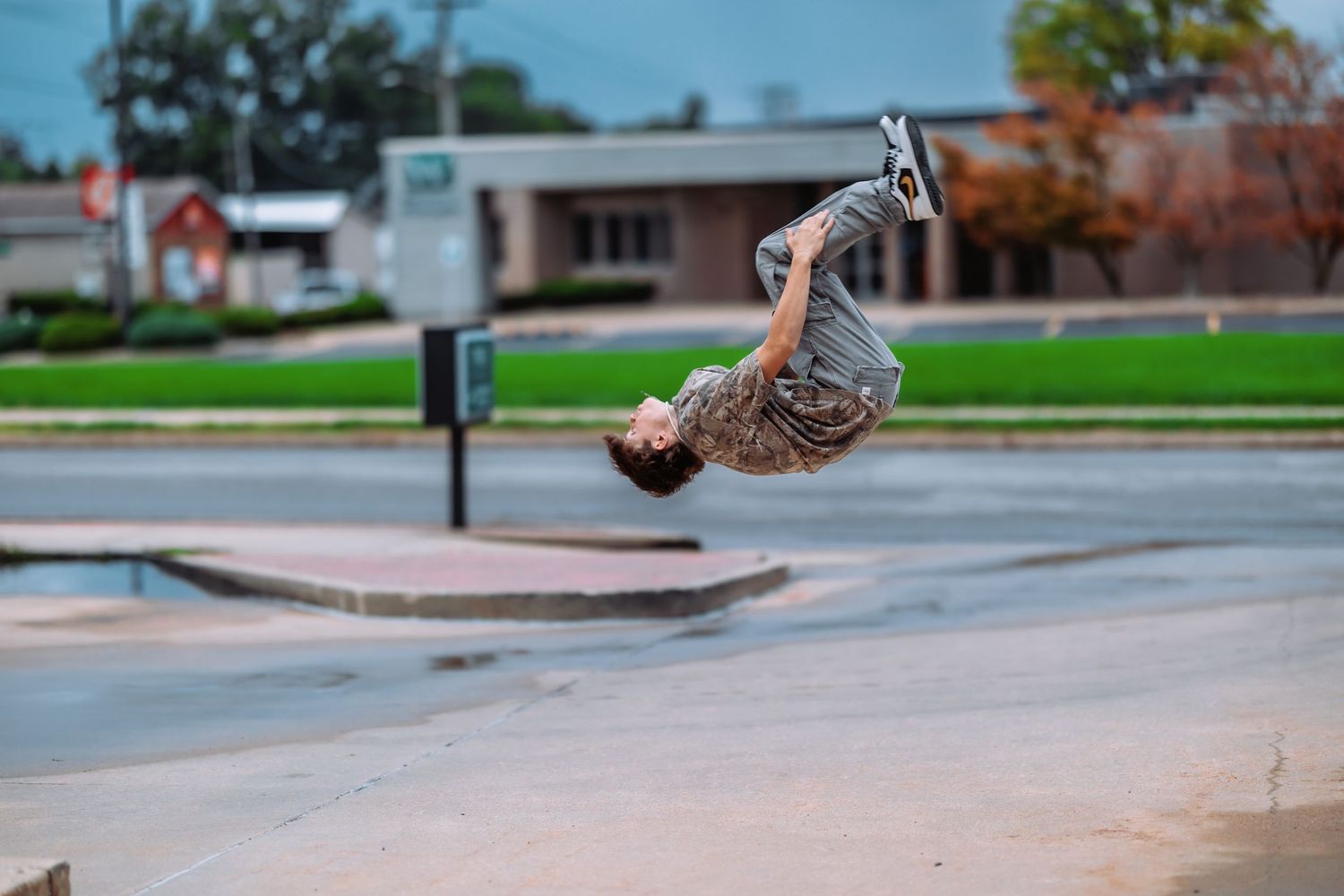 A skateboarder performs a sequence of aerial tricks on a concrete skate park ramp during daytime.