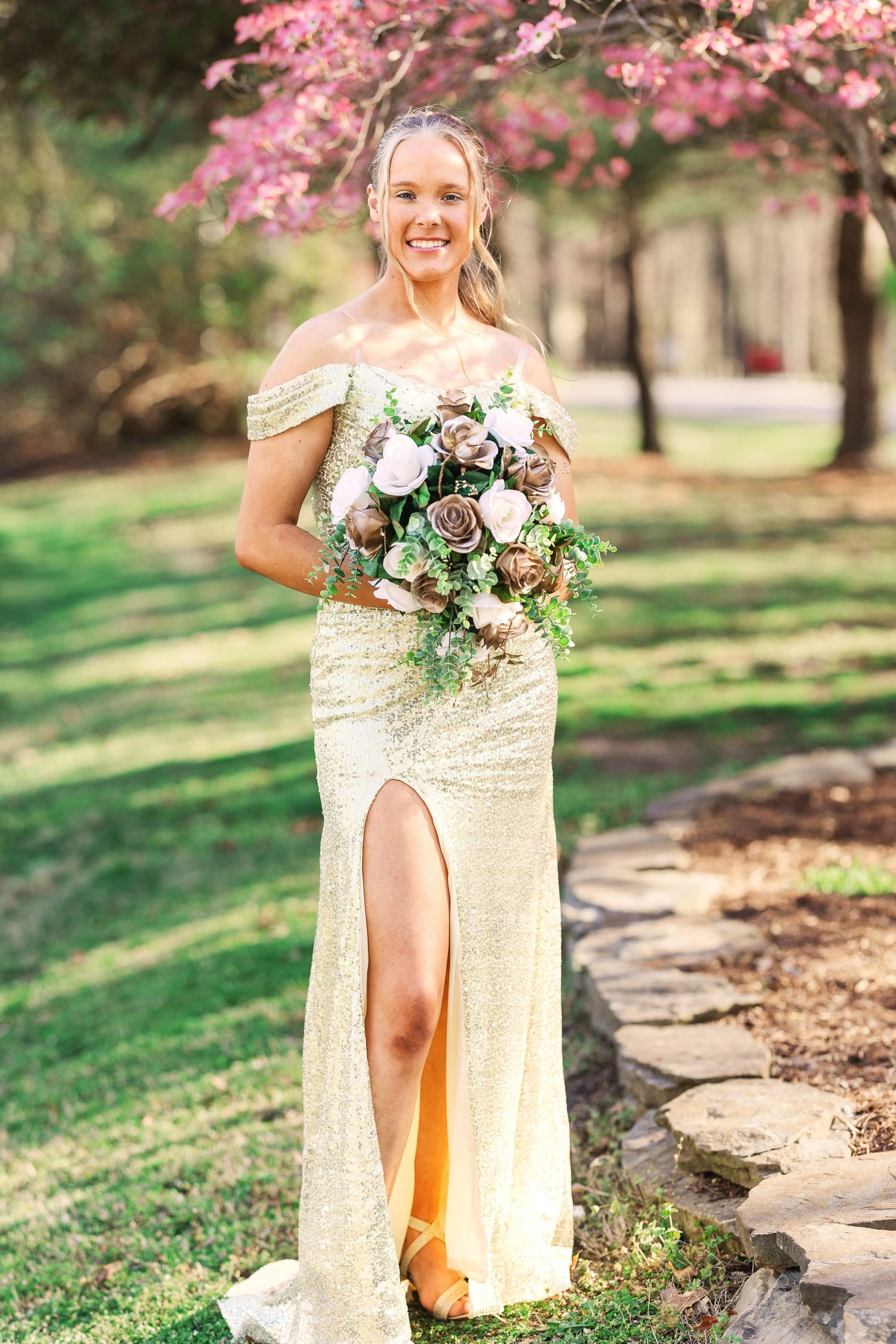 Gold sequin formal dress photographed under blooming cherry blossom trees.