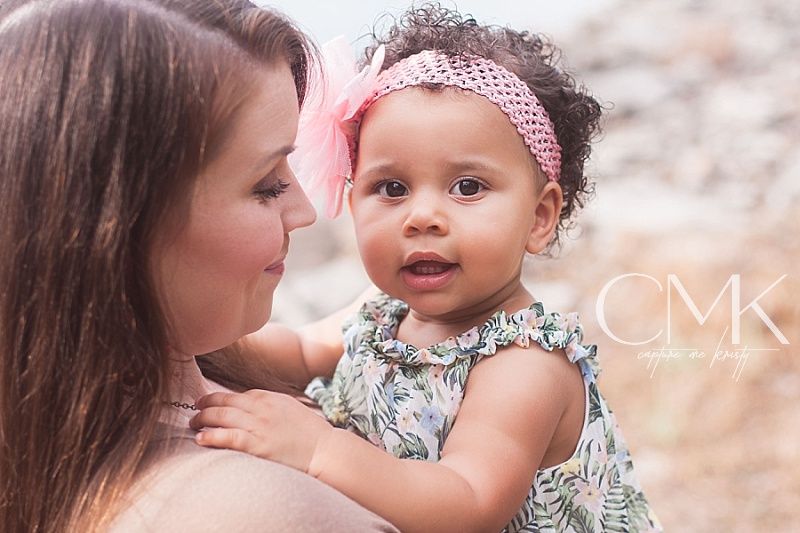 Lifestyle portrait of parent and baby in matching tones with CMK watermark.