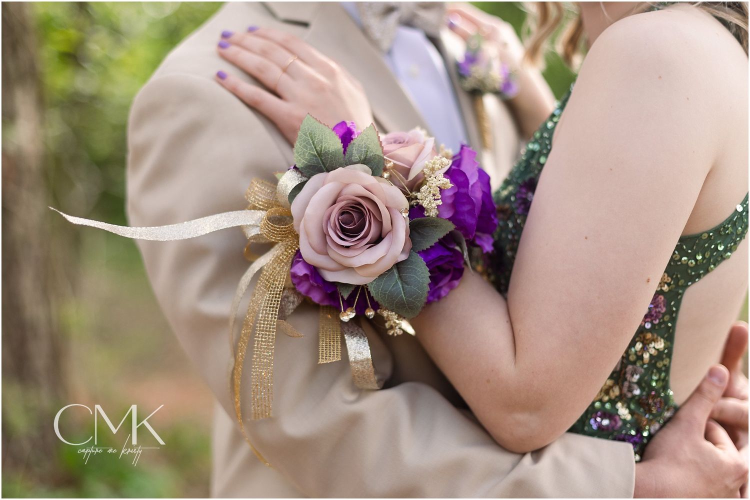 Close-up of a purple and pink rose corsage with ribbons against a tan suit jacket.