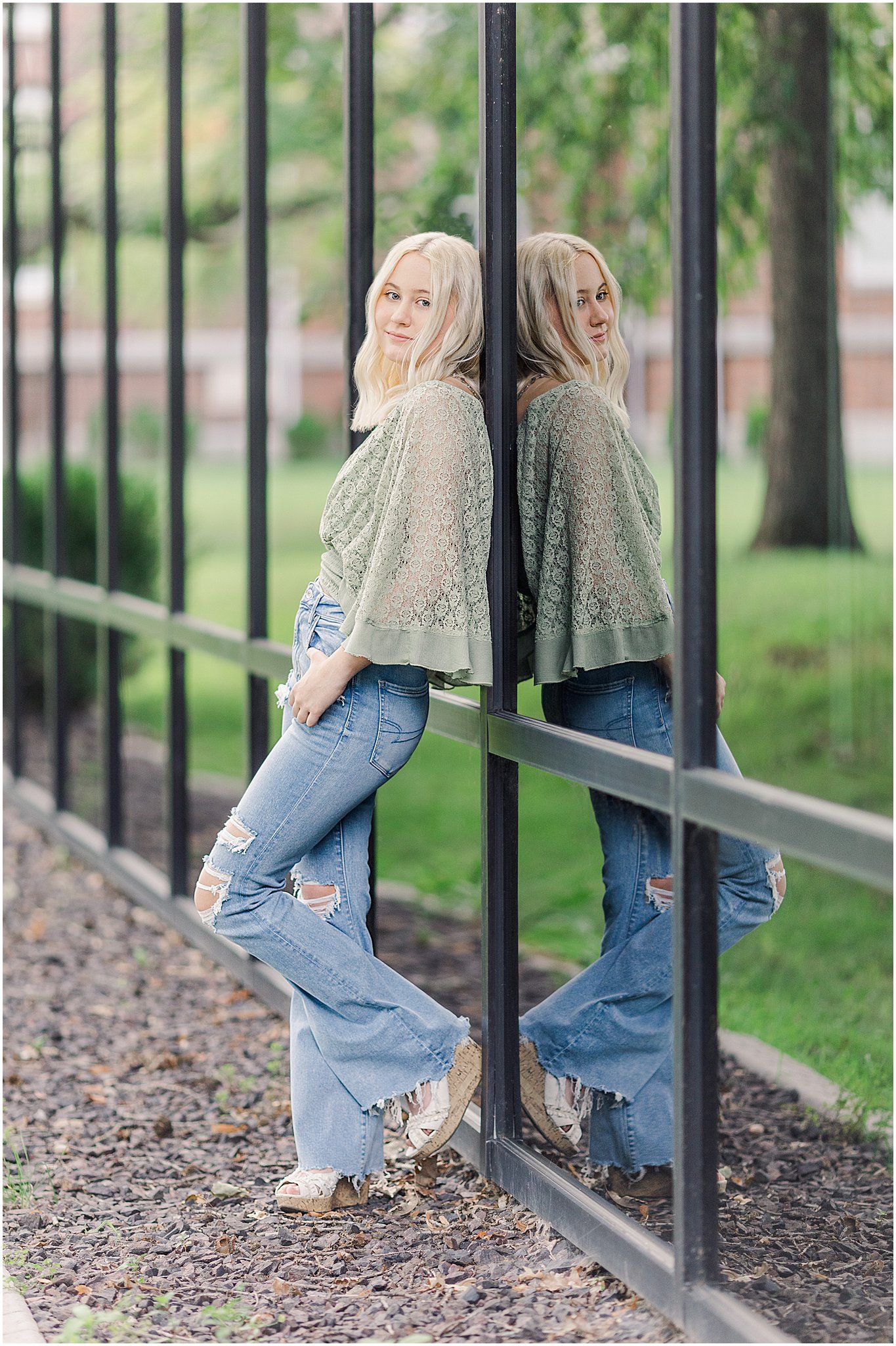 Senior girl leans against black reflective windows