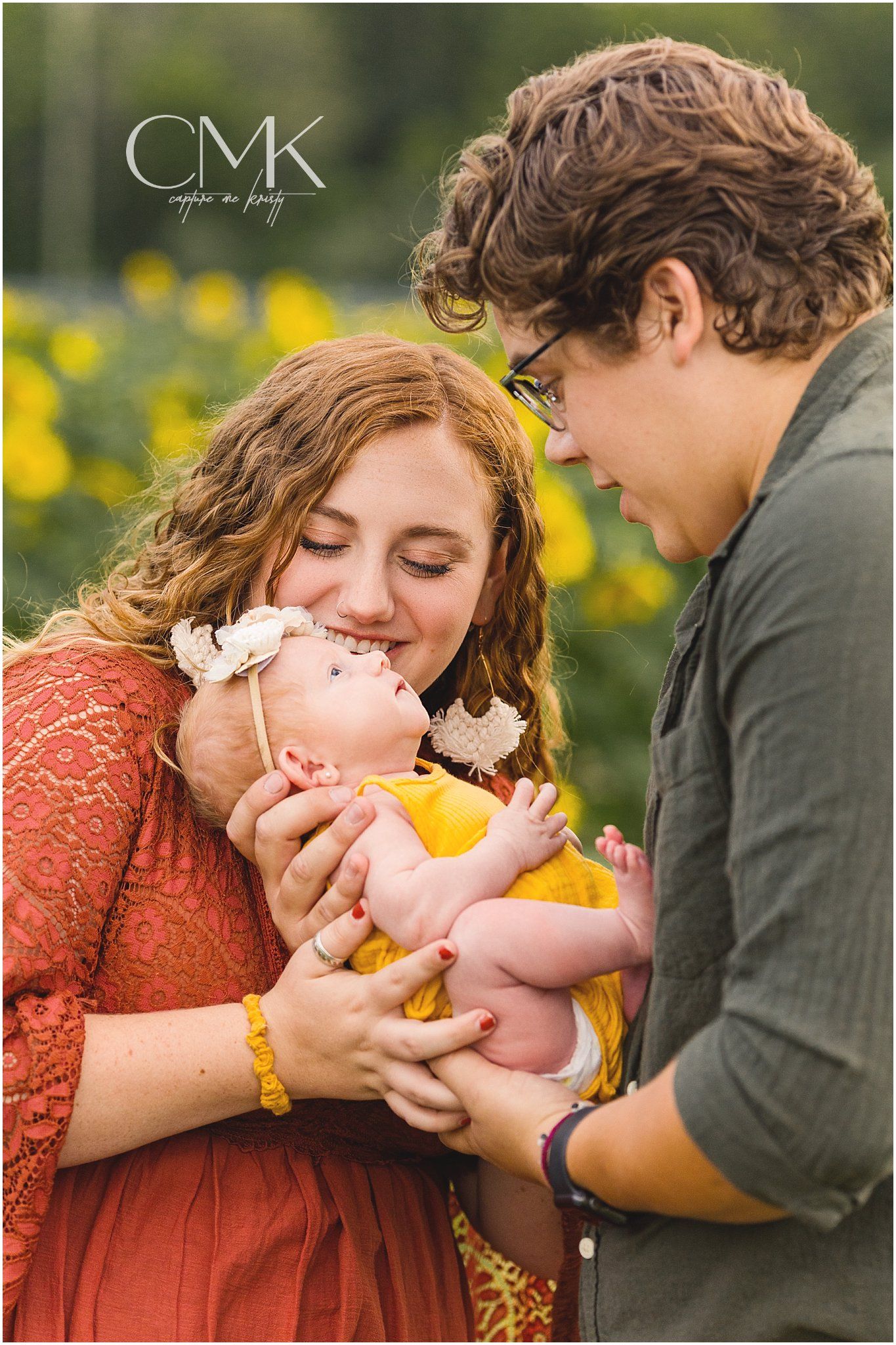 Sweet family moment captured in vertical portrait with baby in yellow outfit.