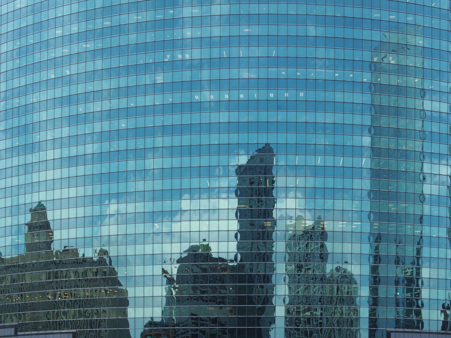 Photograph of a Chicago, Illinois skyscraper with additional buildings reflected in the glass facade.  Taken during a river cruise.