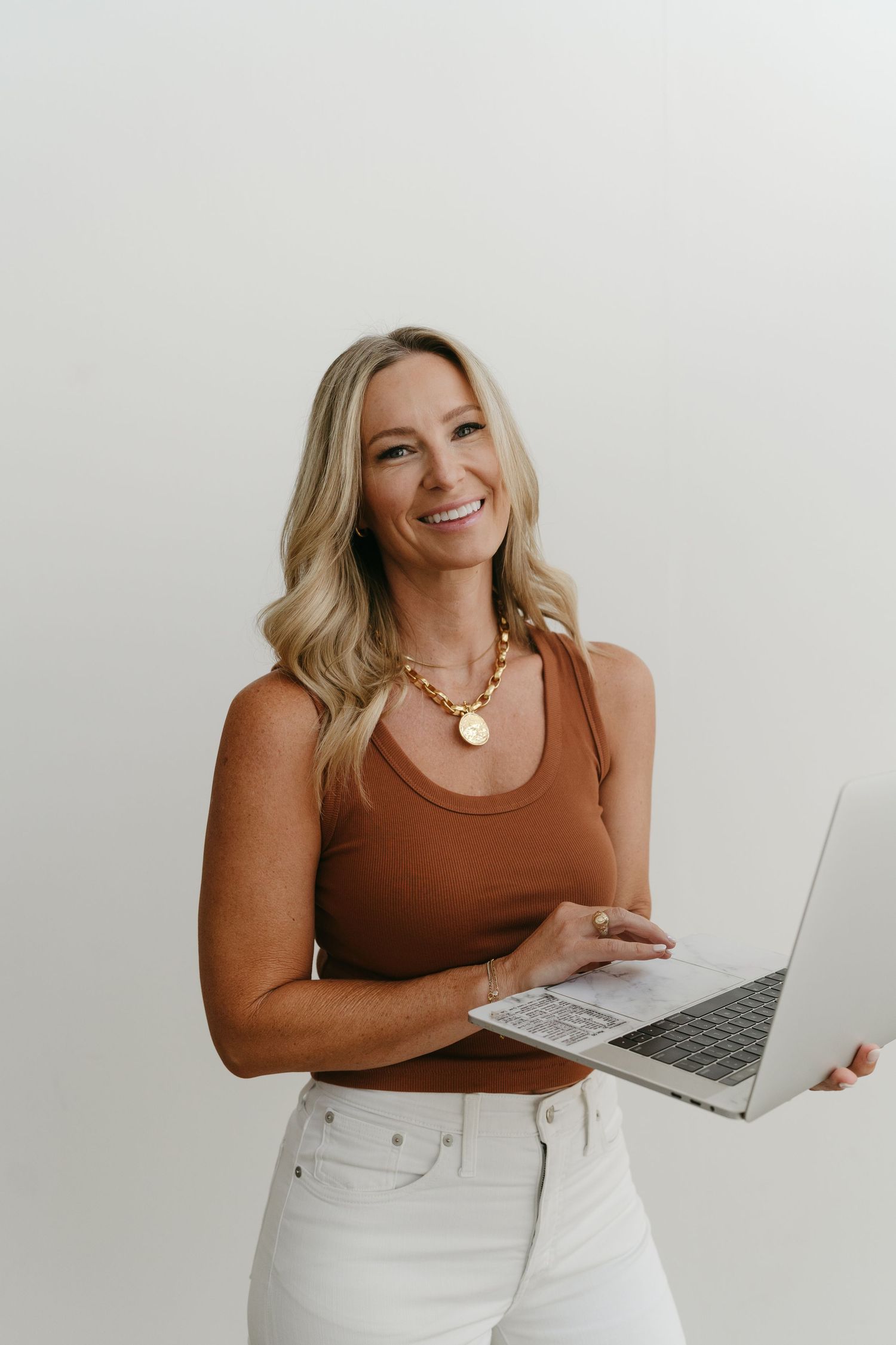 Business lifestyle photos showing person with laptop in brown top and white pants.