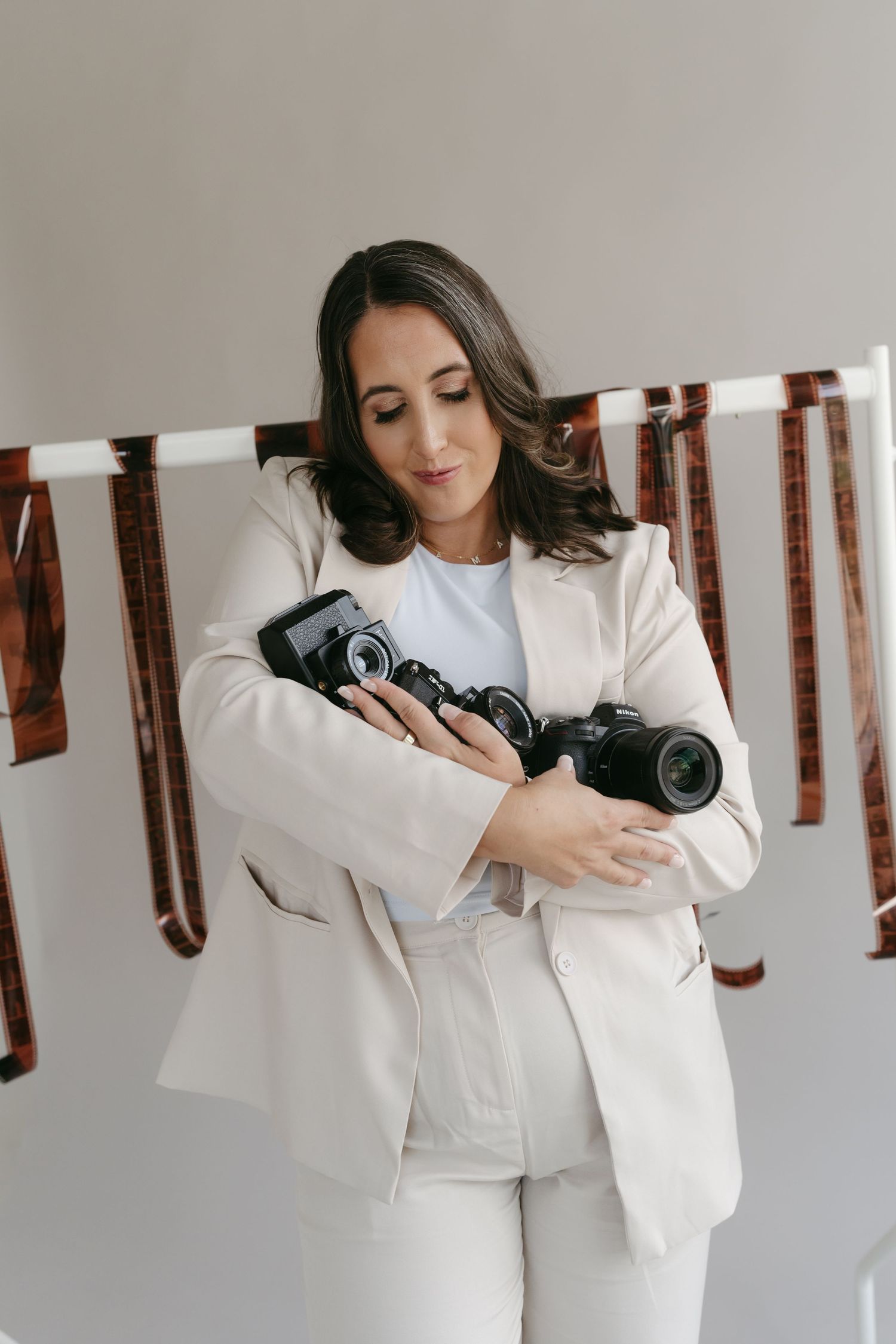 Photographer in white suit demonstrates camera handling techniques in studio.