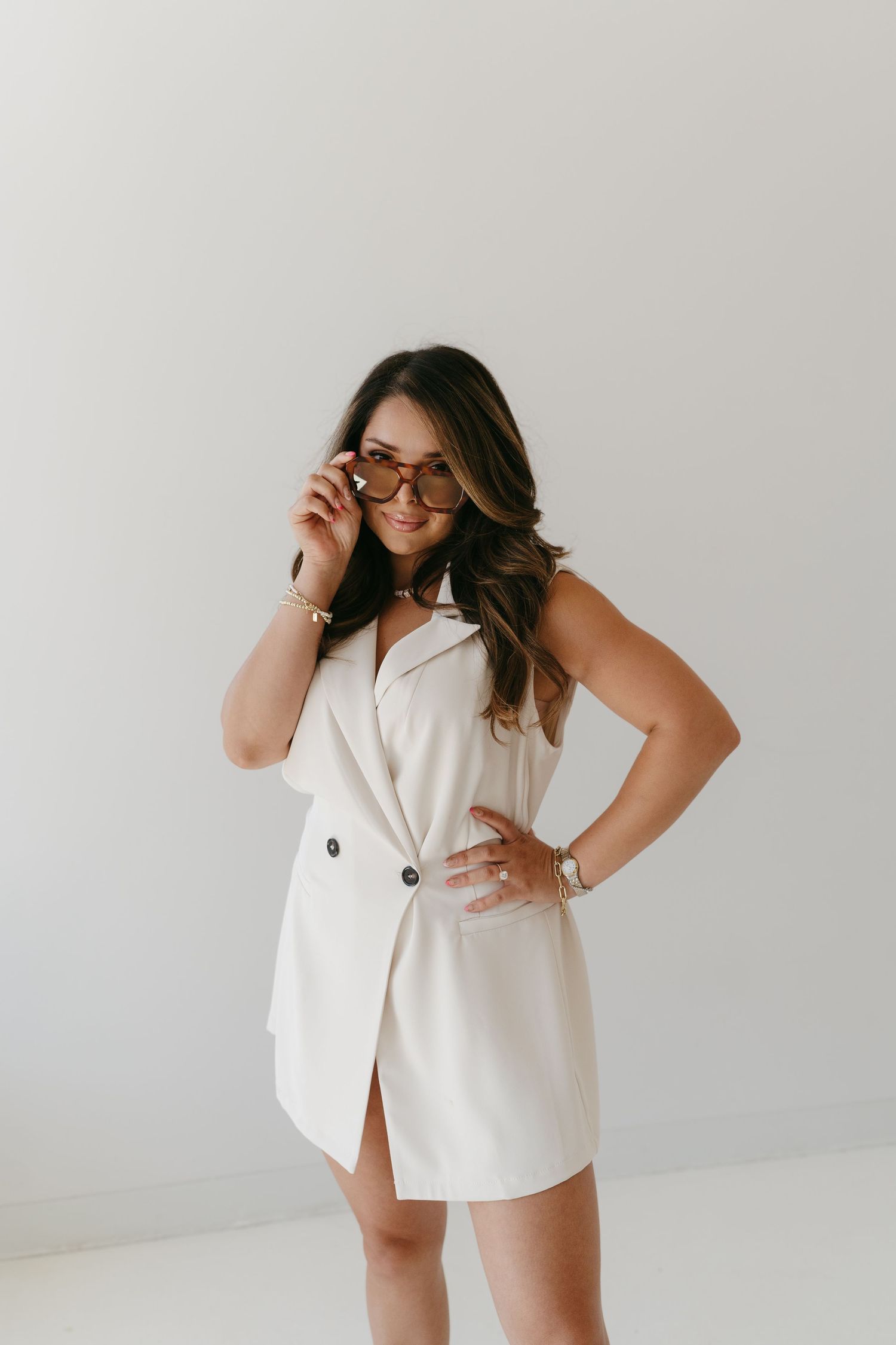 Fashion portrait series in white sleeveless outfit showing confident poses against neutral background.