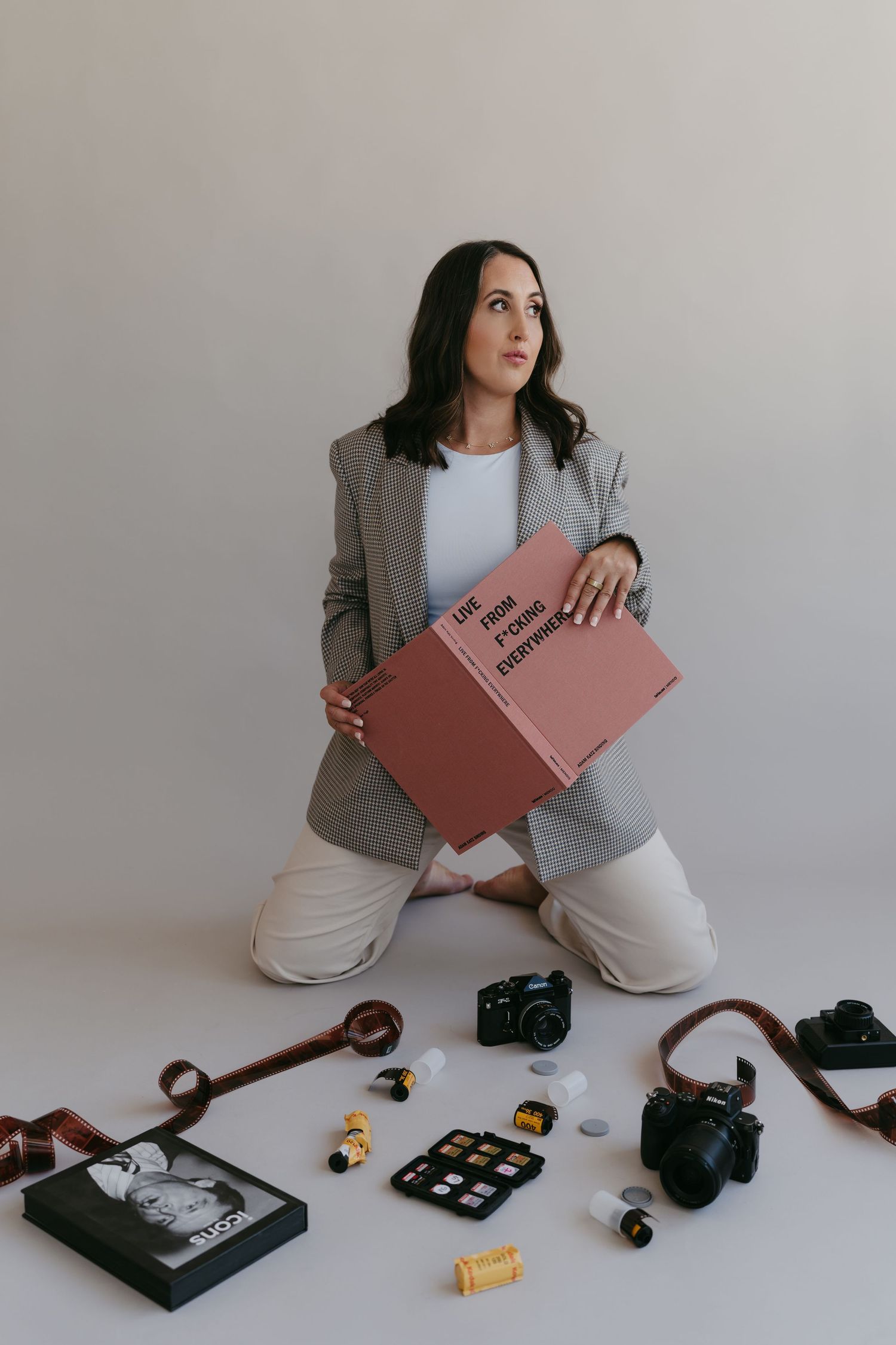 Photographer arranges camera equipment and accessories on white floor in studio setting.