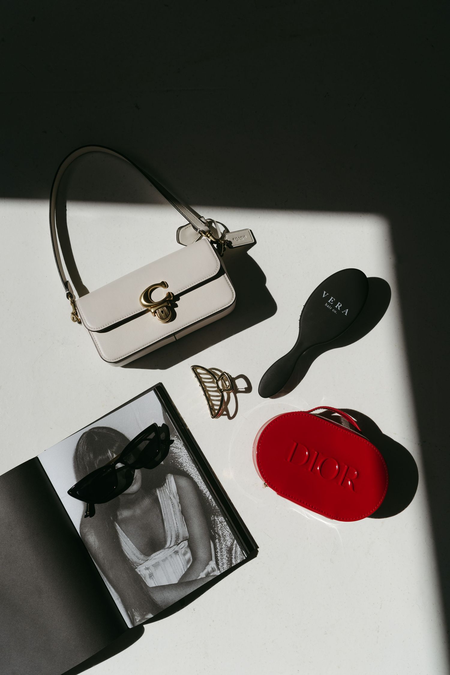 Still life composition with sunglasses, purse and red shoe casting dramatic shadows.