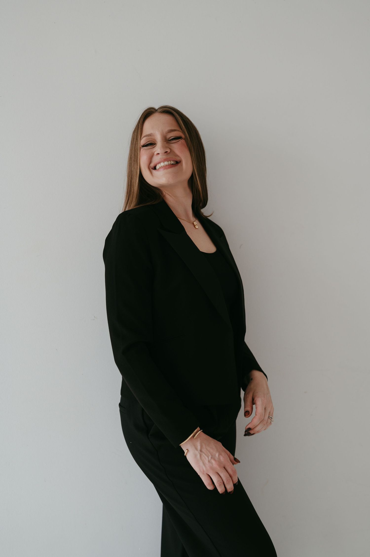 A series of photos showing someone in a black sweater posing and laughing against a white wall.