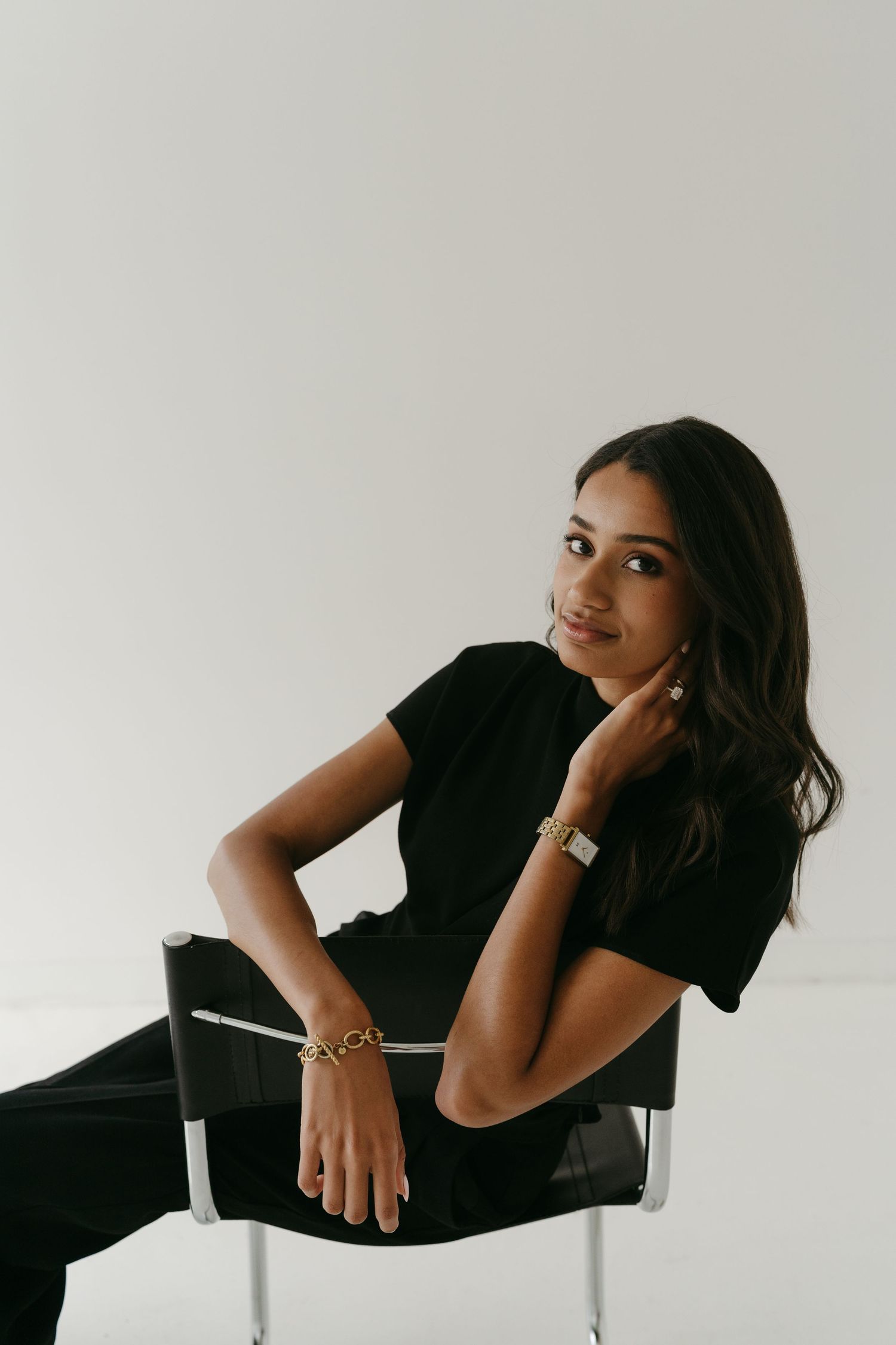 Minimalist studio portrait in black outfit against white background.