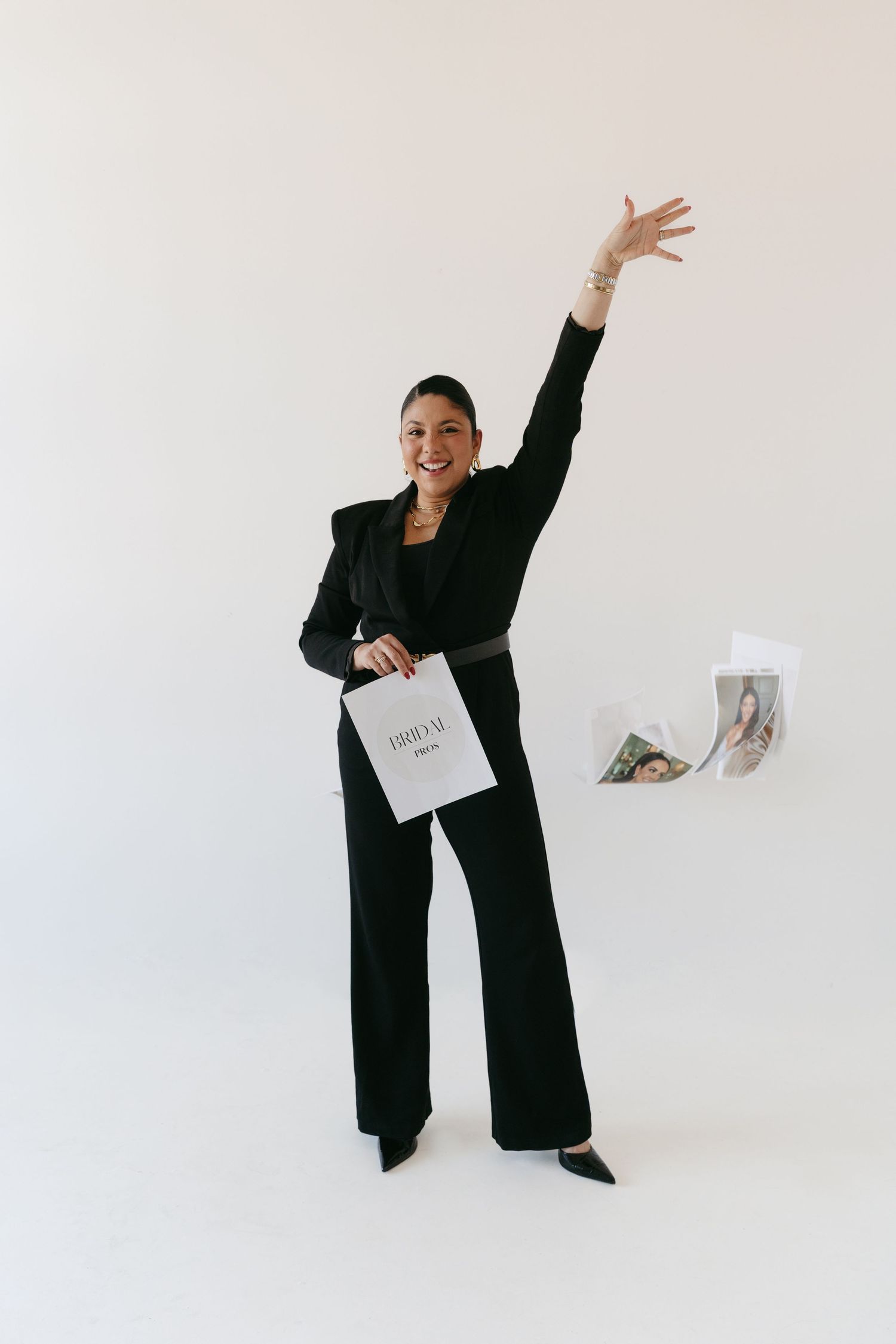 Figure in black business suit dances and throws papers in white studio setting.