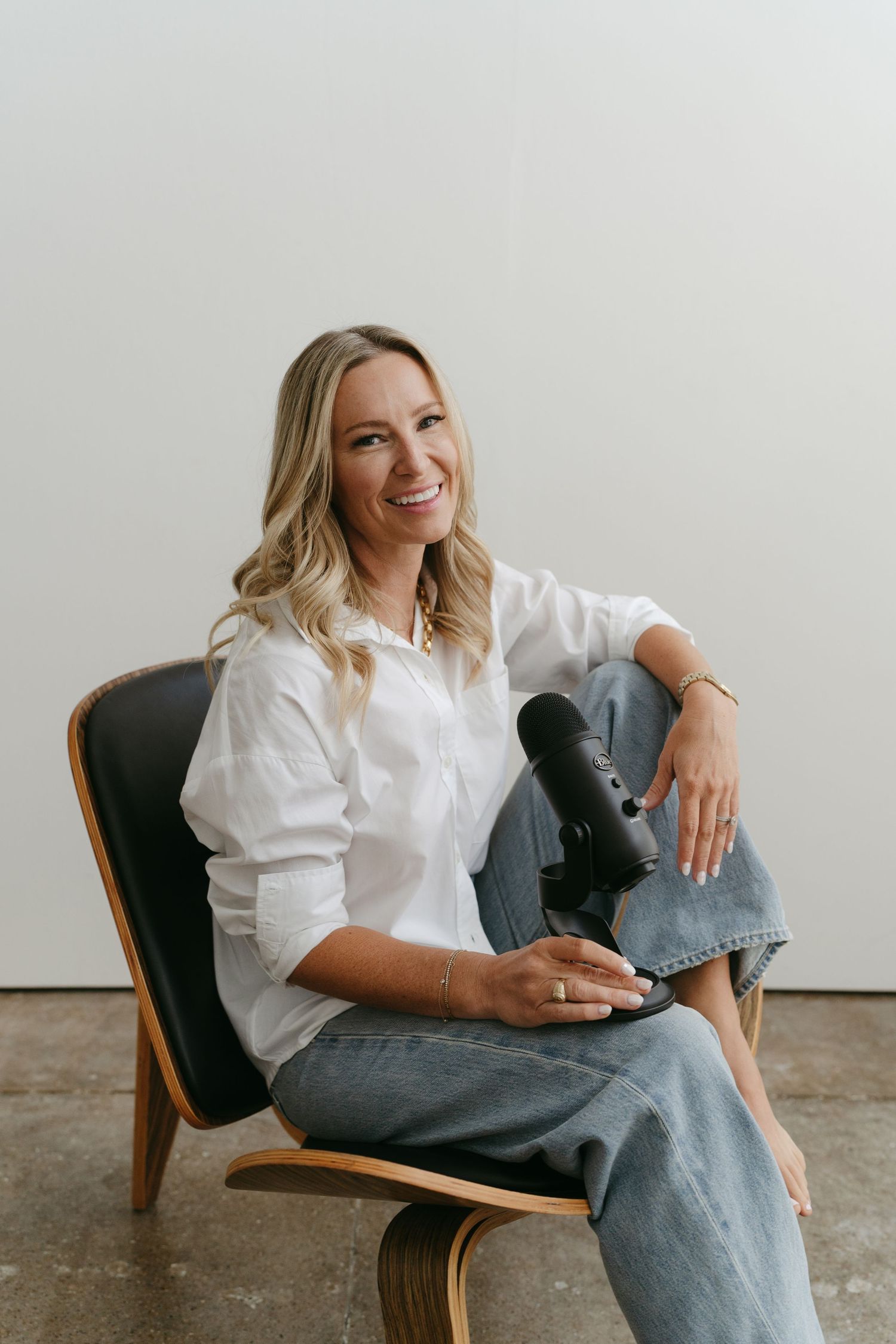 Lifestyle portraits of person in white shirt and jeans lounging in modern chair.
