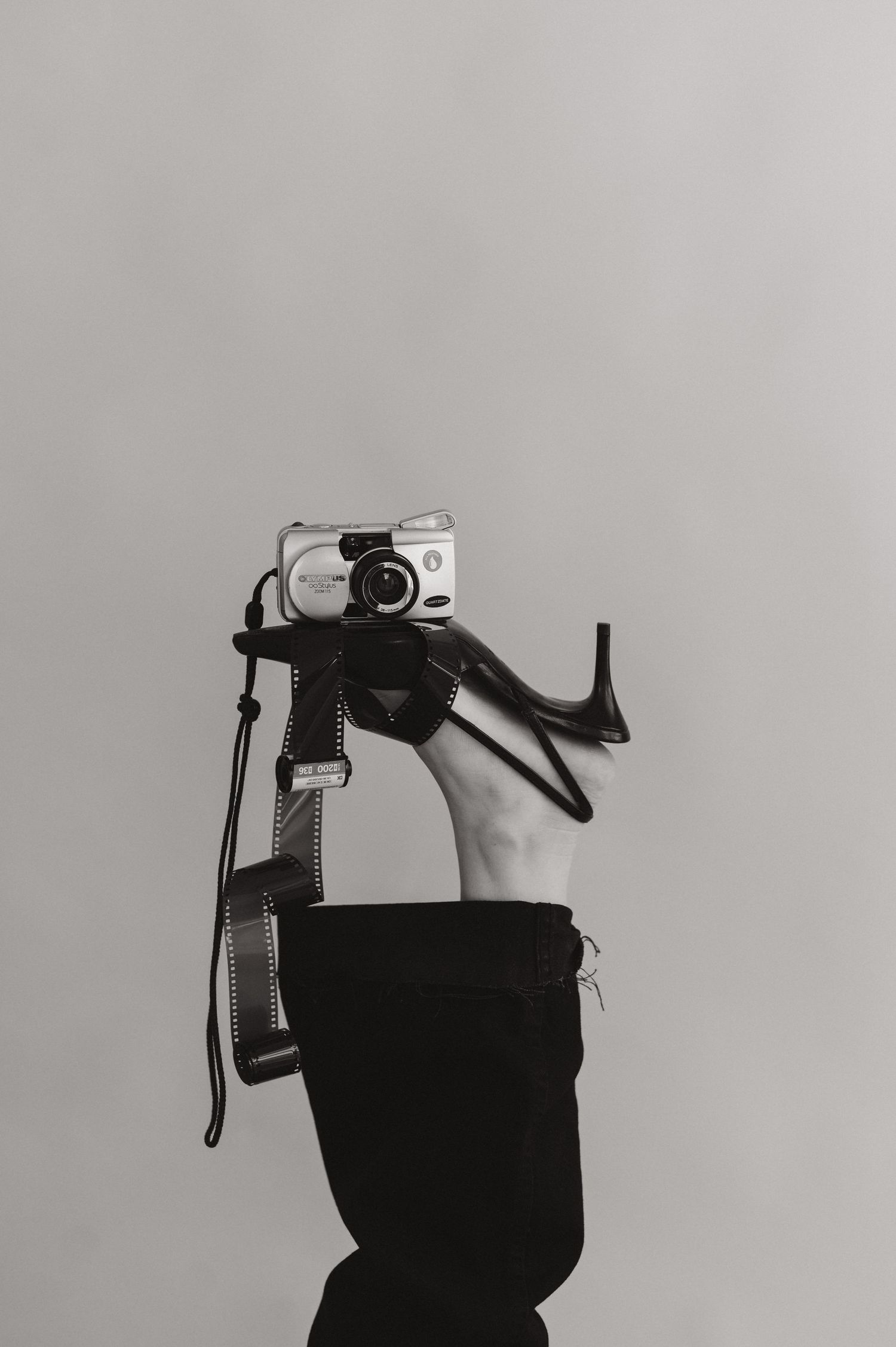 Hand holding a vintage point-and-shoot camera against a minimalist gray background.