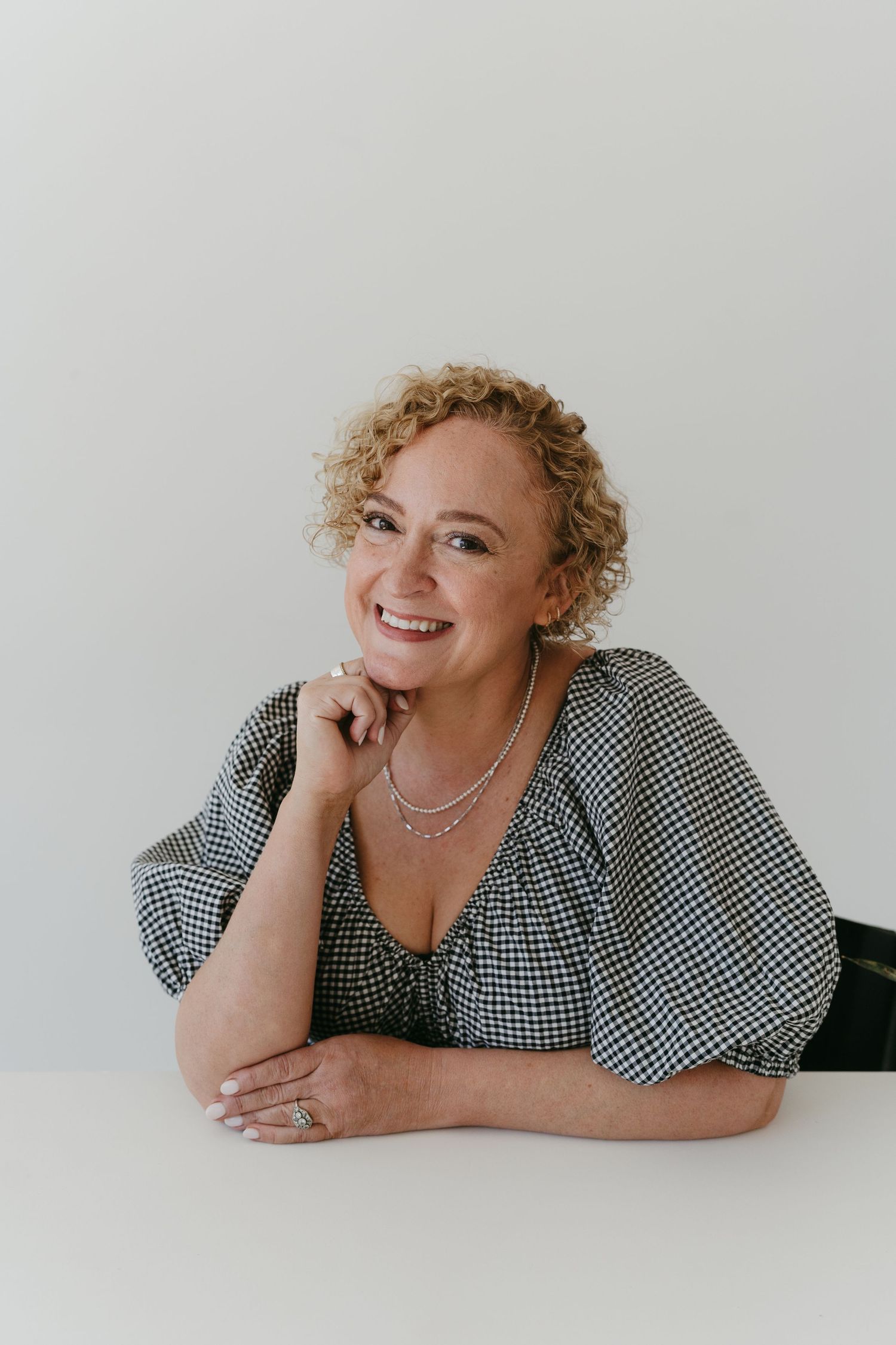 Creative portrait session showing person in checkered top lying on white background.