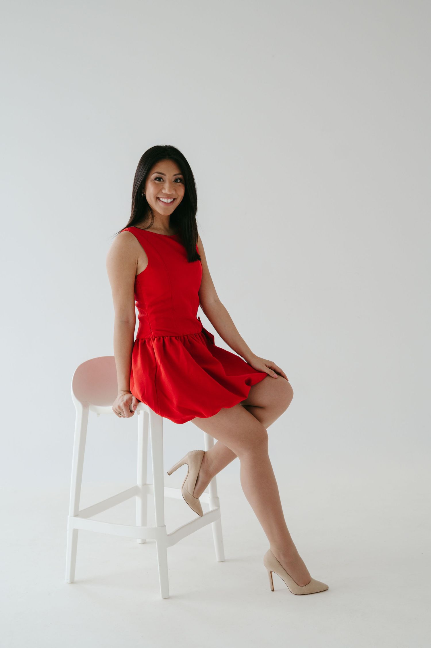A series of four photos showing a person in a red dress posing elegantly on a white chair against a light background.