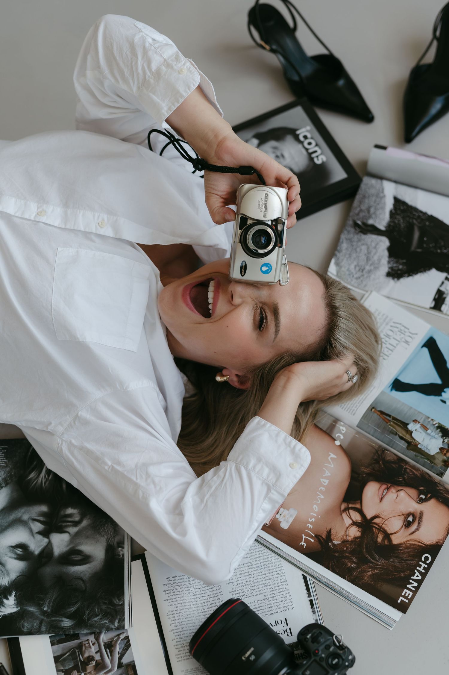 Creative overhead shot with vintage camera and fashion magazines on white surface.