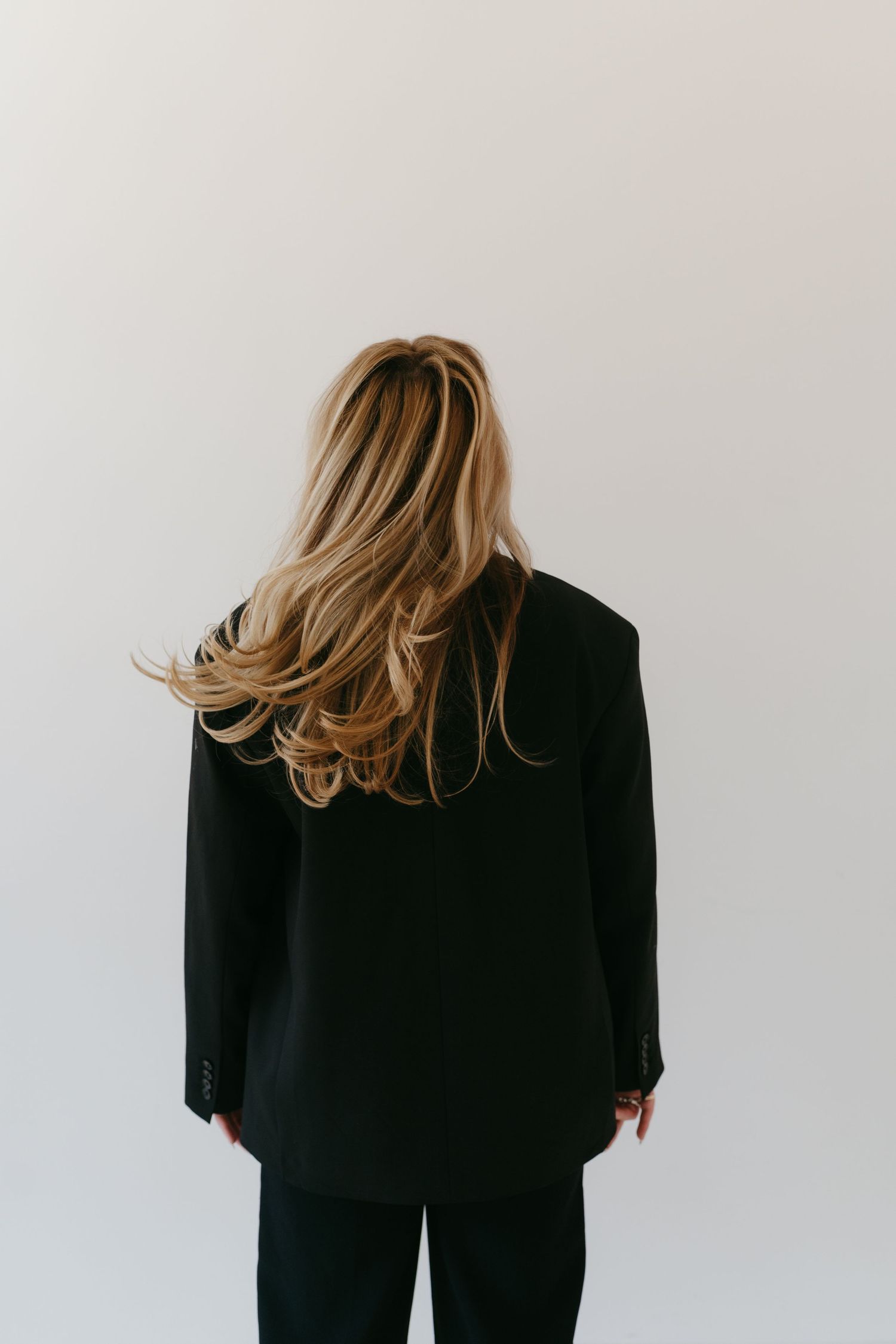 Artistic portrait series showing back view of person in black outfit against white background.