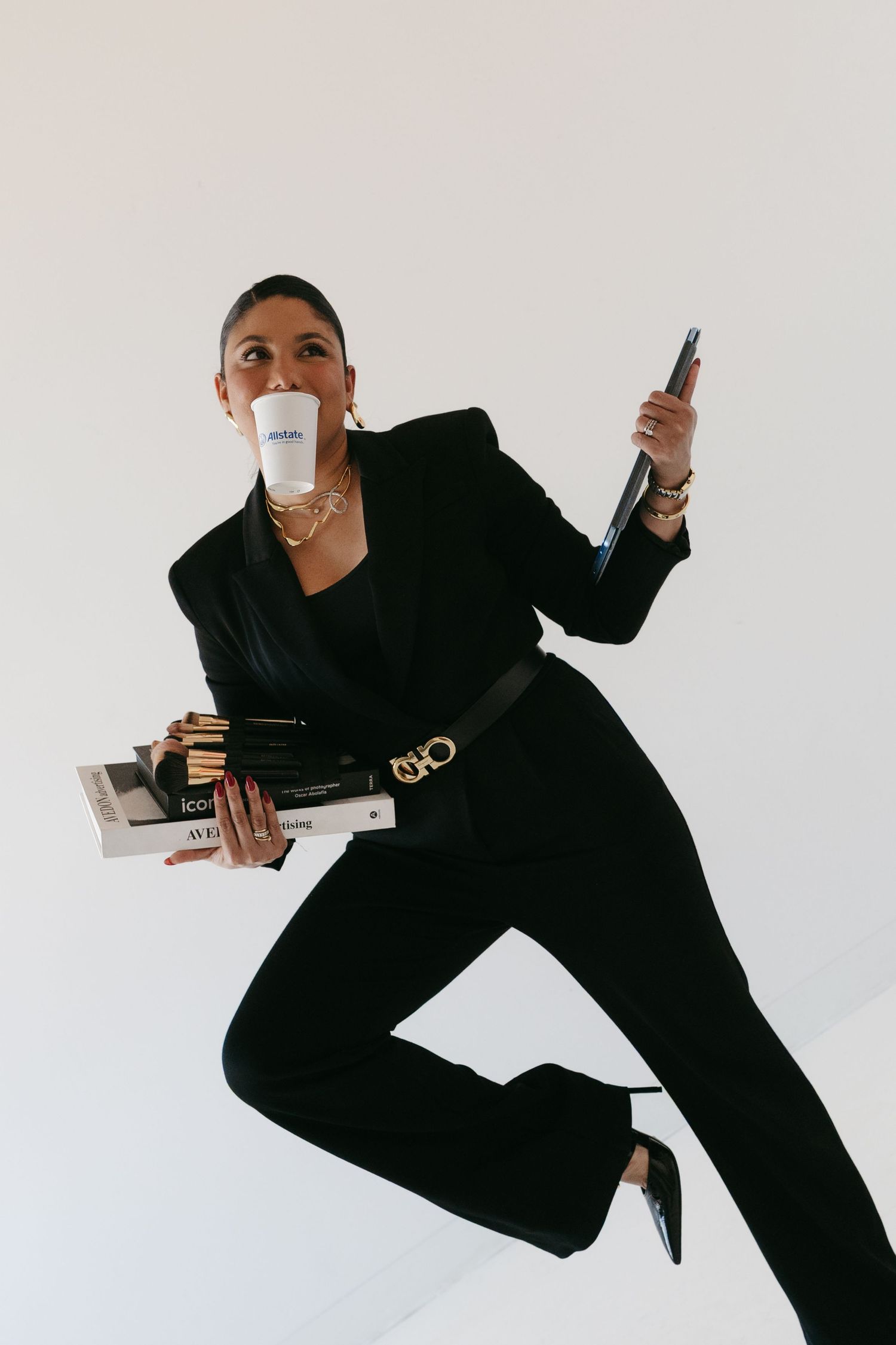 Dynamic shots of person in black suit moving with papers and phone against white backdrop.