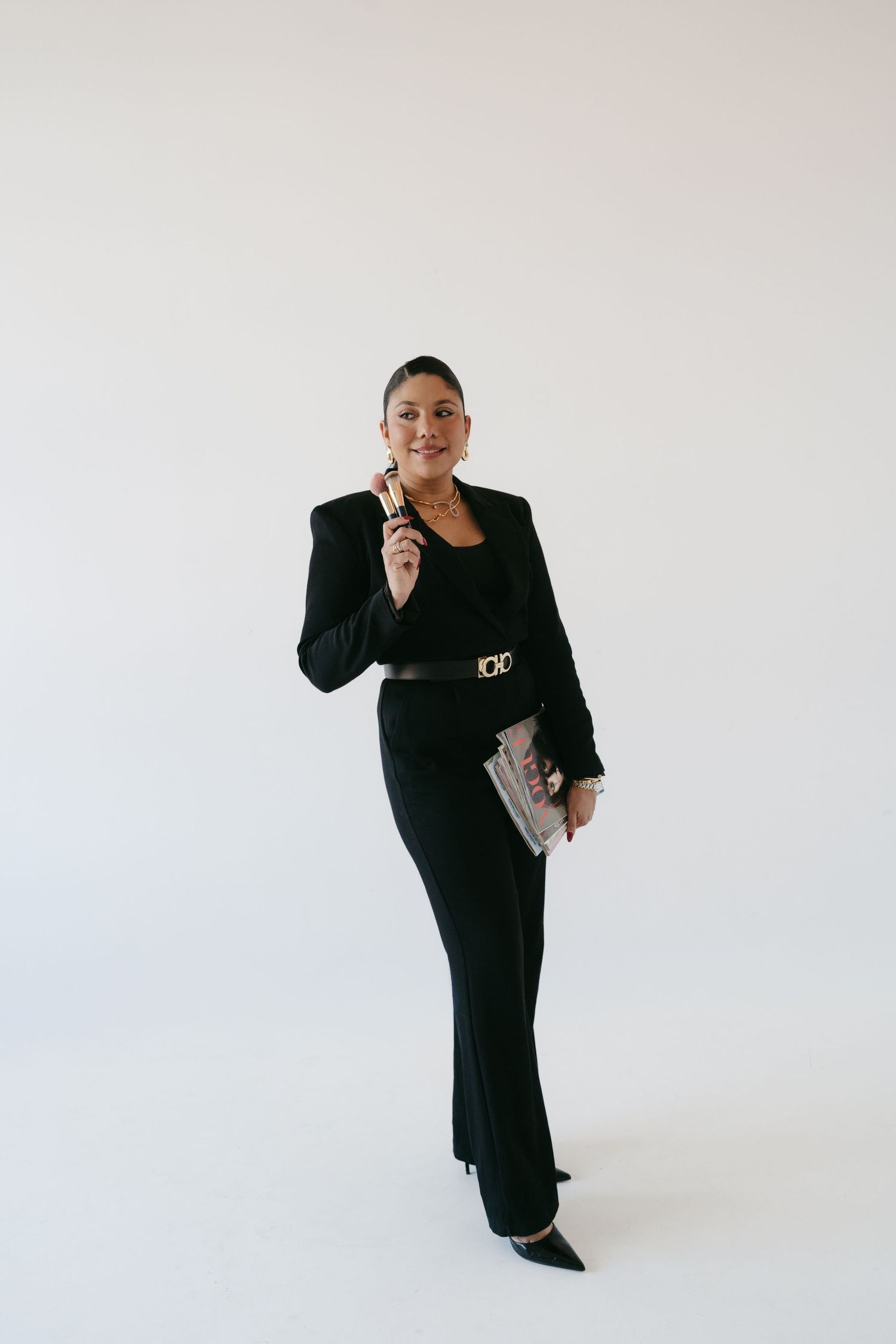 Person in black outfit striking playful poses with phone and papers.