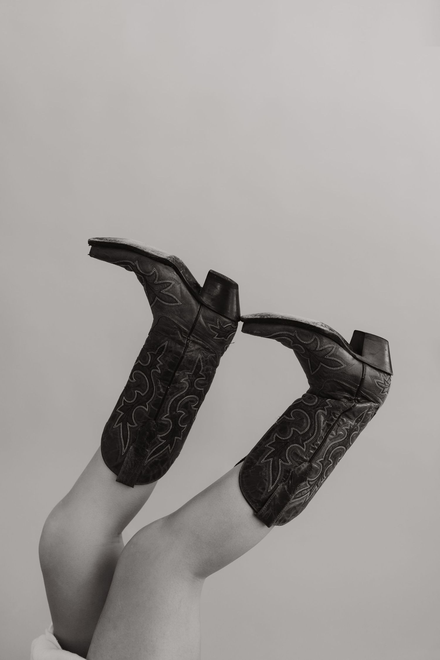 Close-up of black patterned boots shown in various angles against grey background.