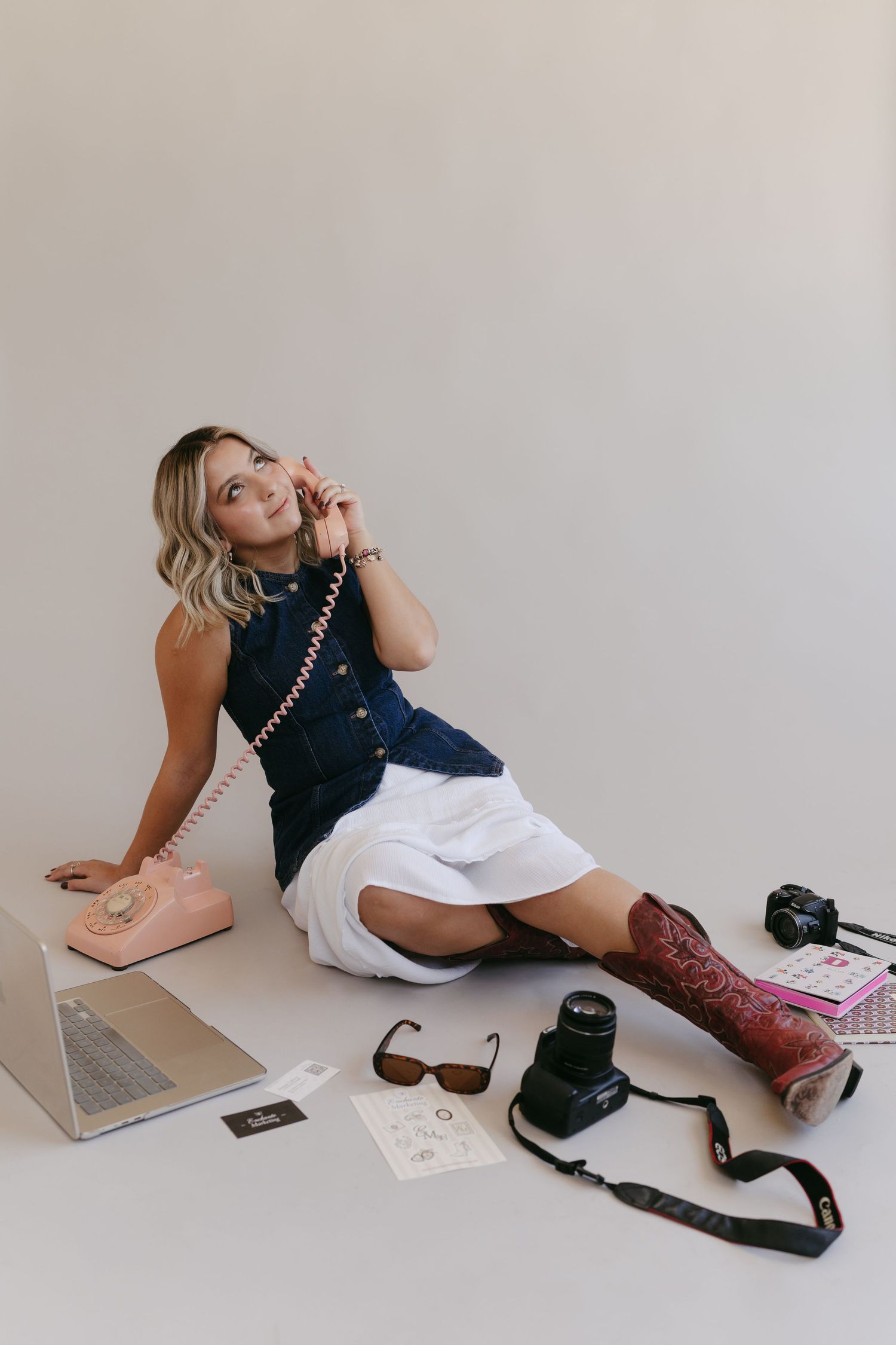 Model lounges on floor with camera equipment and red boots in artistic photography setup.