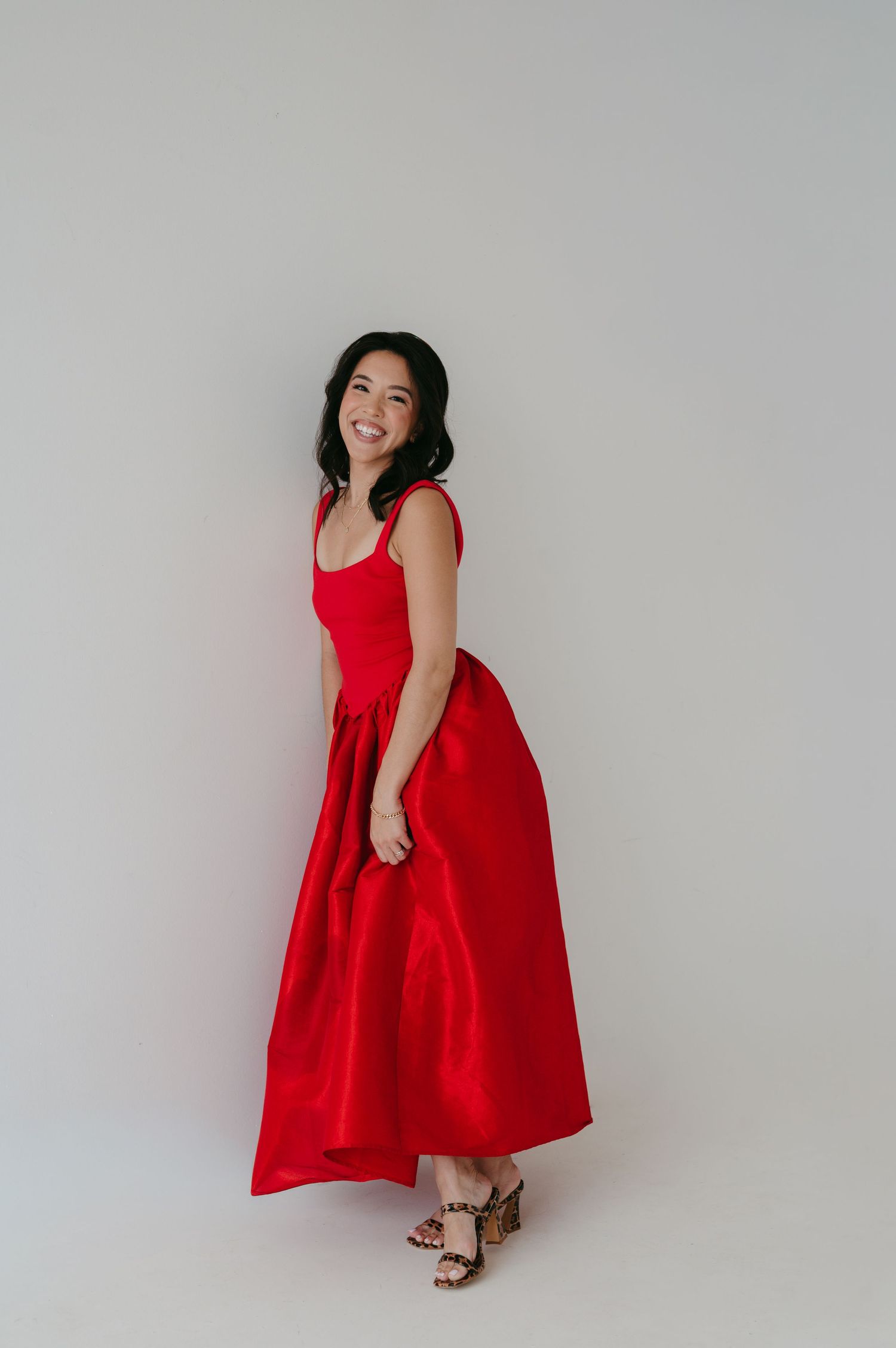 A vibrant red sleeveless dress is modeled against a white background in a series of fashion poses.