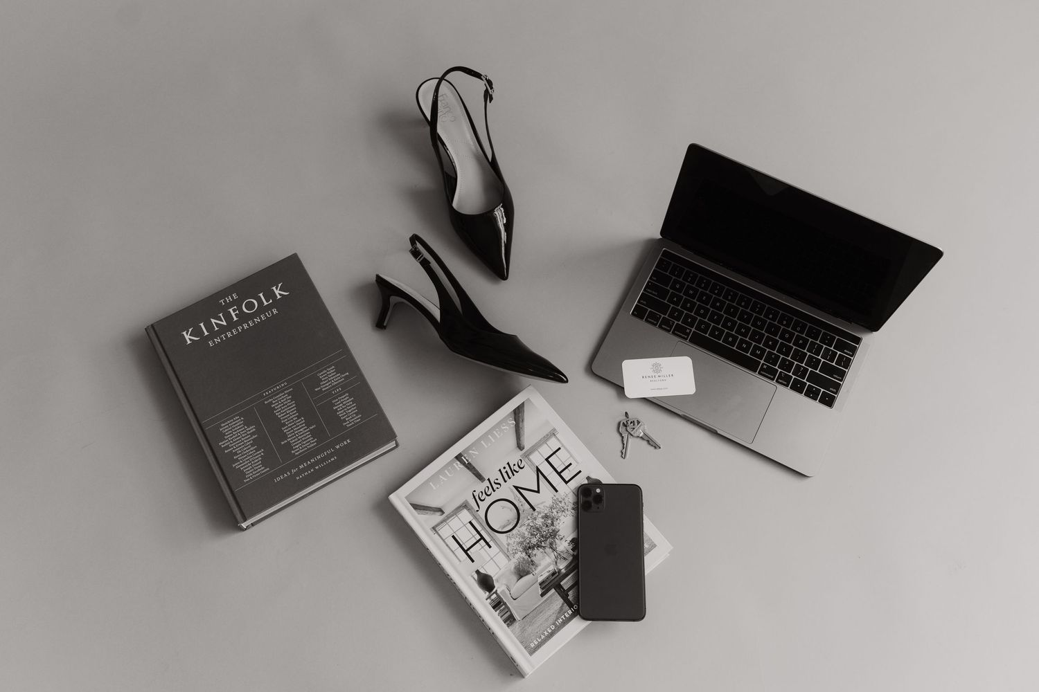 Flatlay of books, black high heels, and laptop on gray background.