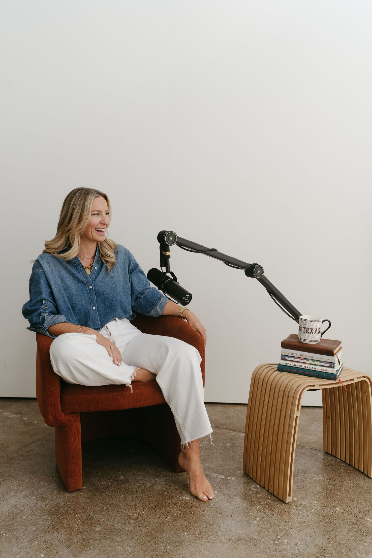 Relaxed content creation setup with person on brown chair and wooden side table.
