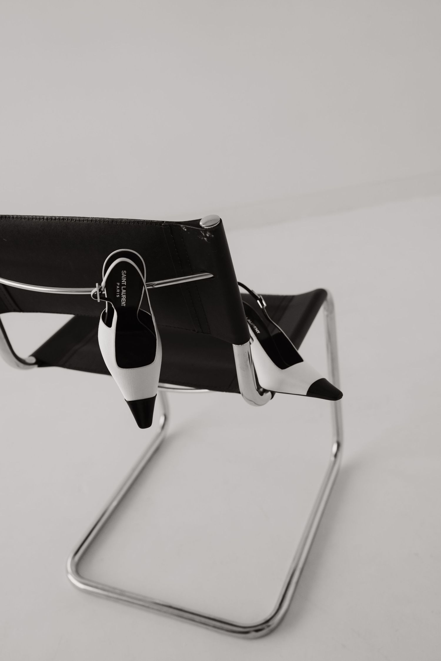 Black and white heels displayed on metal stand against white background.