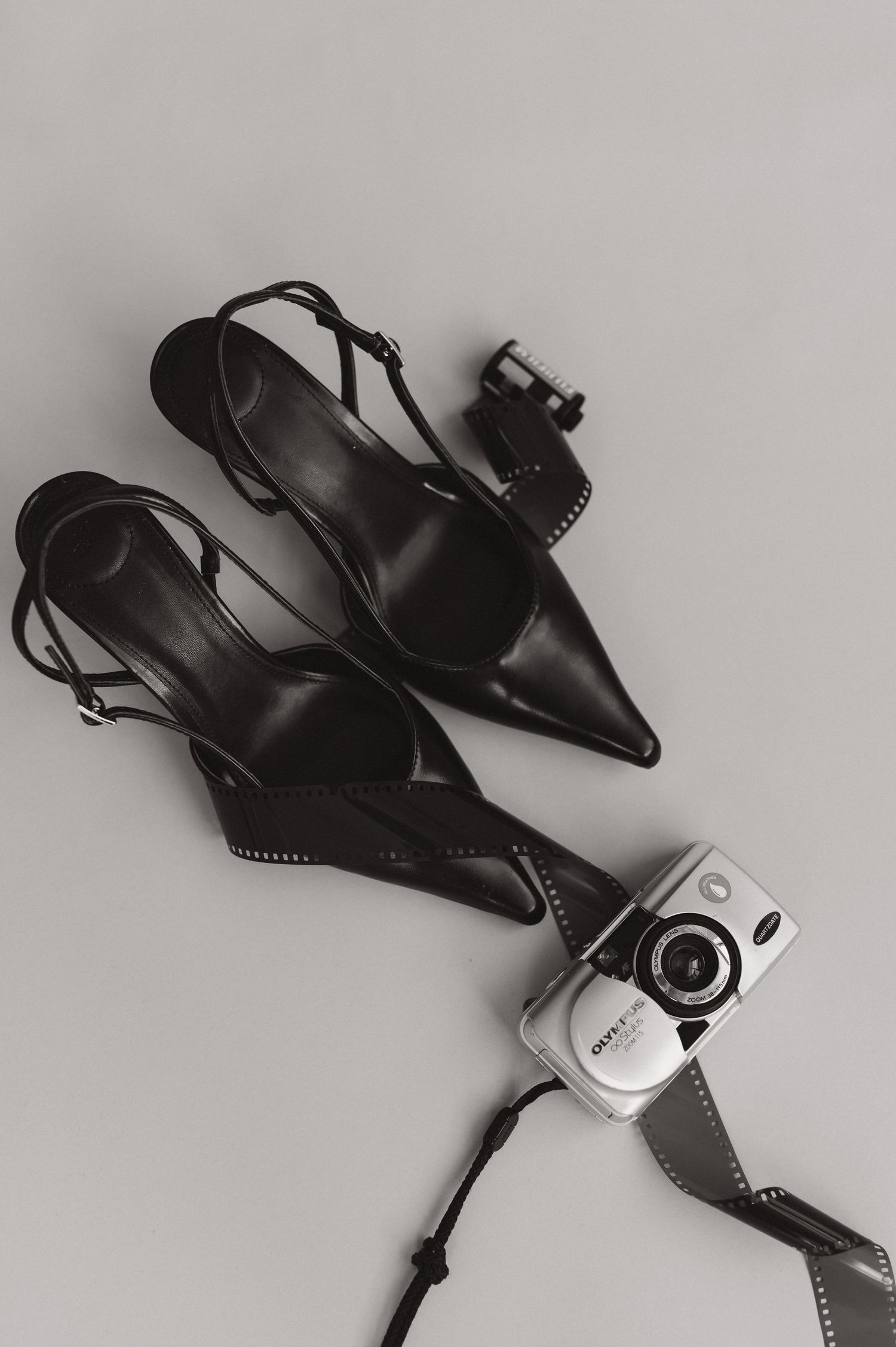 Black camera equipment and accessories arranged artistically on light gray background.
