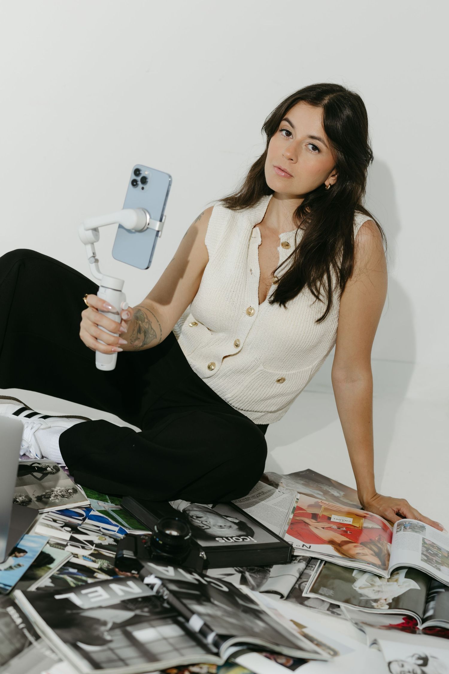 Person in cream top lounges on floor surrounded by scattered photographs.