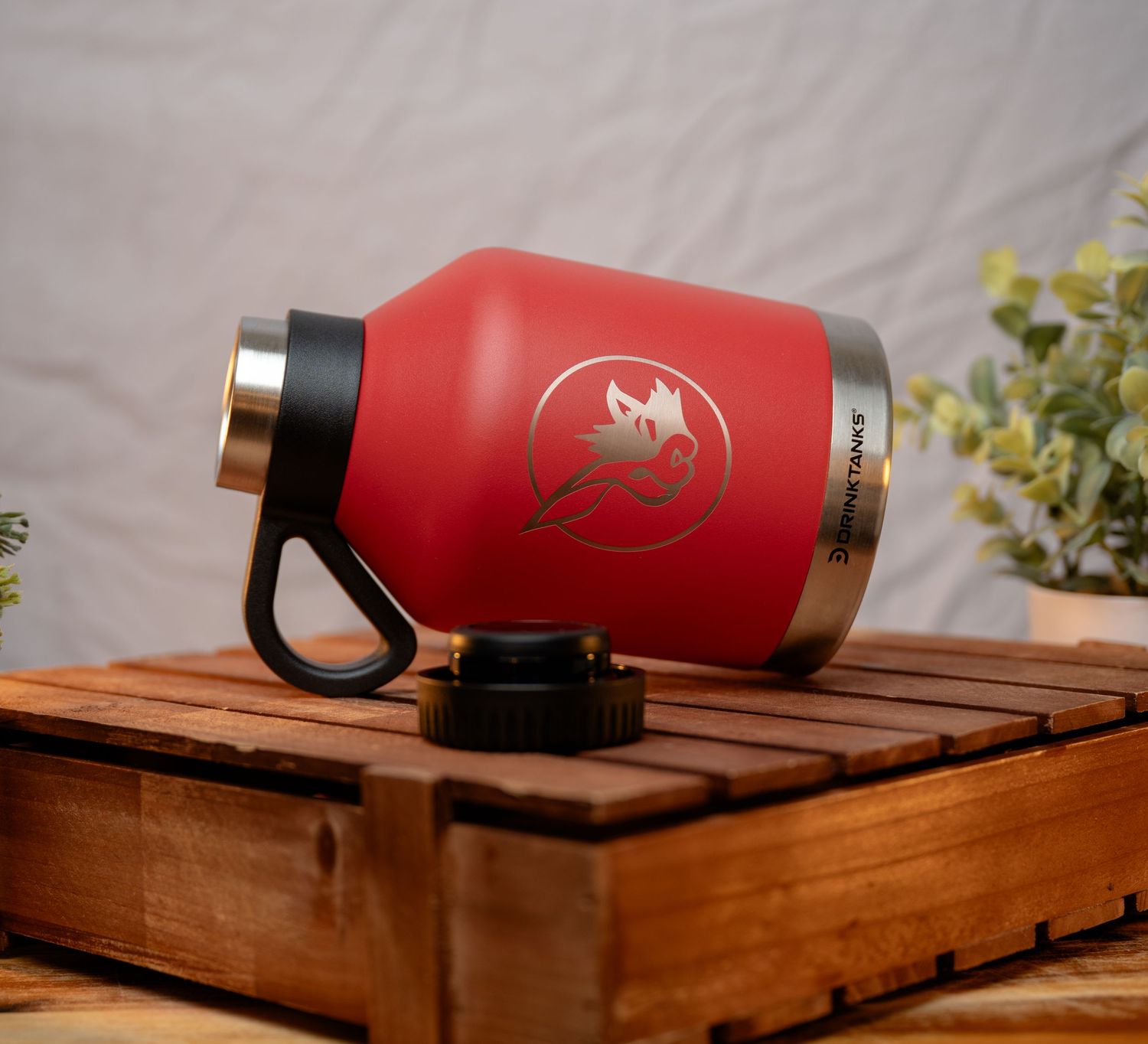Red insulated water bottles displayed on wooden pallet surface against white background.