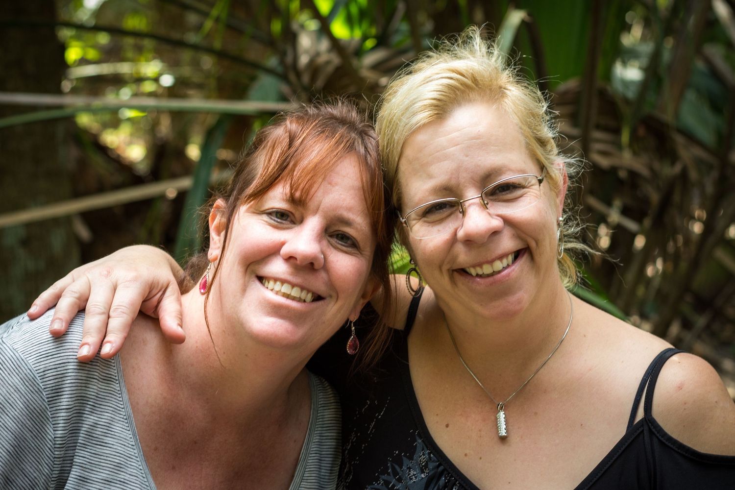 Two people enjoying a sunny day outdoors with bright smiles.