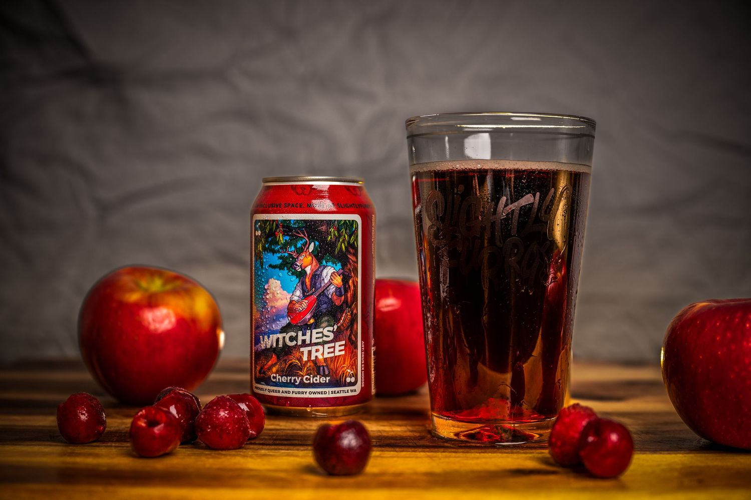 Cozy still life with red apples, candle, and glass of whiskey on dark wooden surface.