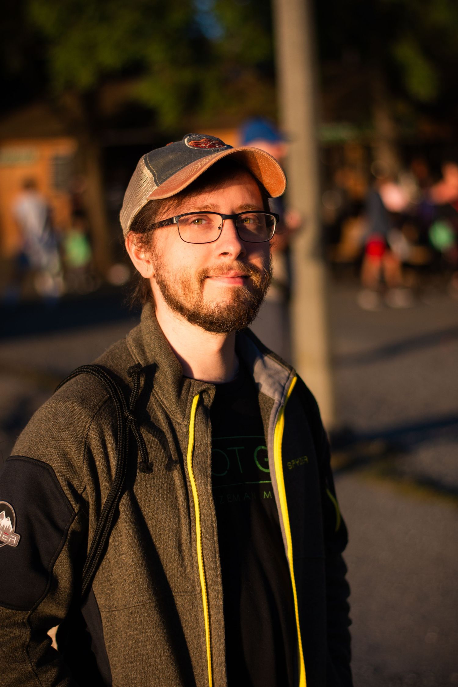 A person in casual outdoor wear and baseball cap photographed at golden hour.