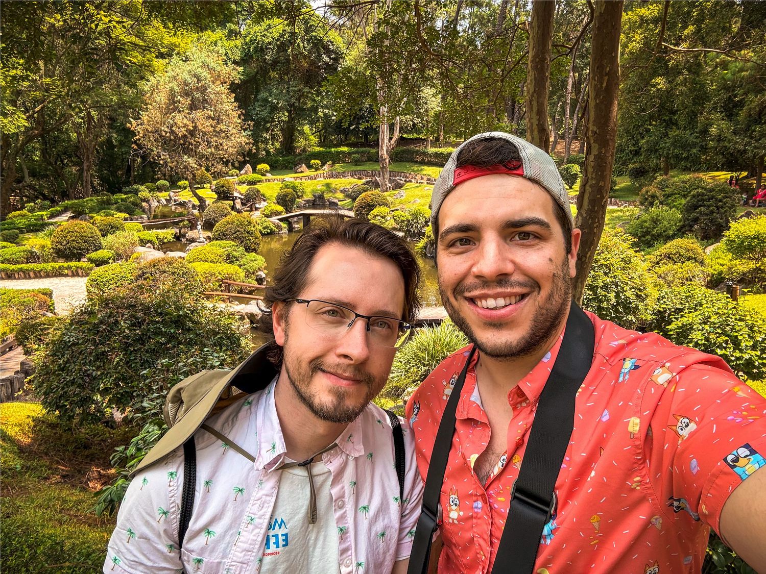 People enjoying a sunny day in a lush Japanese garden with vibrant greenery.